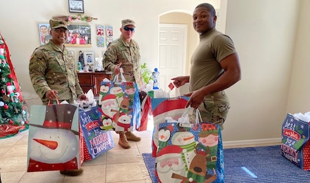 Three men in military uniform carry Christmas bags