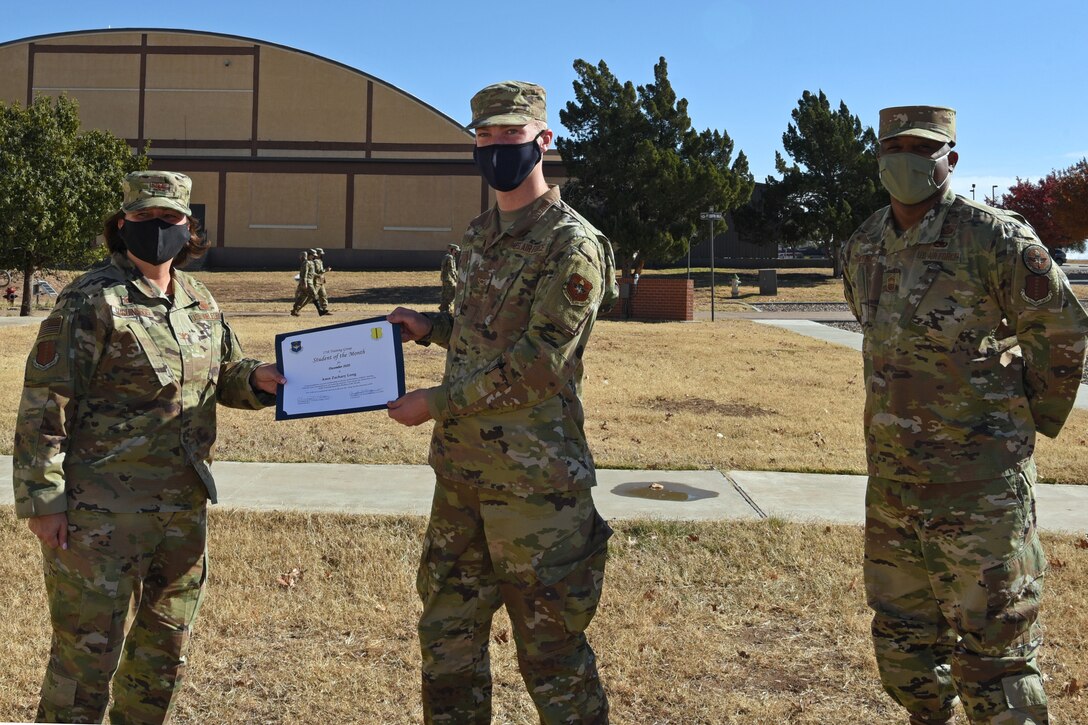 U.S. Air Force Col. Angelina Maguiness, 17th Training Group commander, presents Airman Zachary Long, 312th Training Squadron student, the 312th TRS Student of the Month award outside of the Brandenburg Hall on Goodfellow Air Force Base, Texas, Dec. 11, 2020. Long worked hard for his award and had shown his dedication to his squadron and the training he received at Goodfellow. (U.S. Air Force photo by Senior Airman Abbey Rieves)
