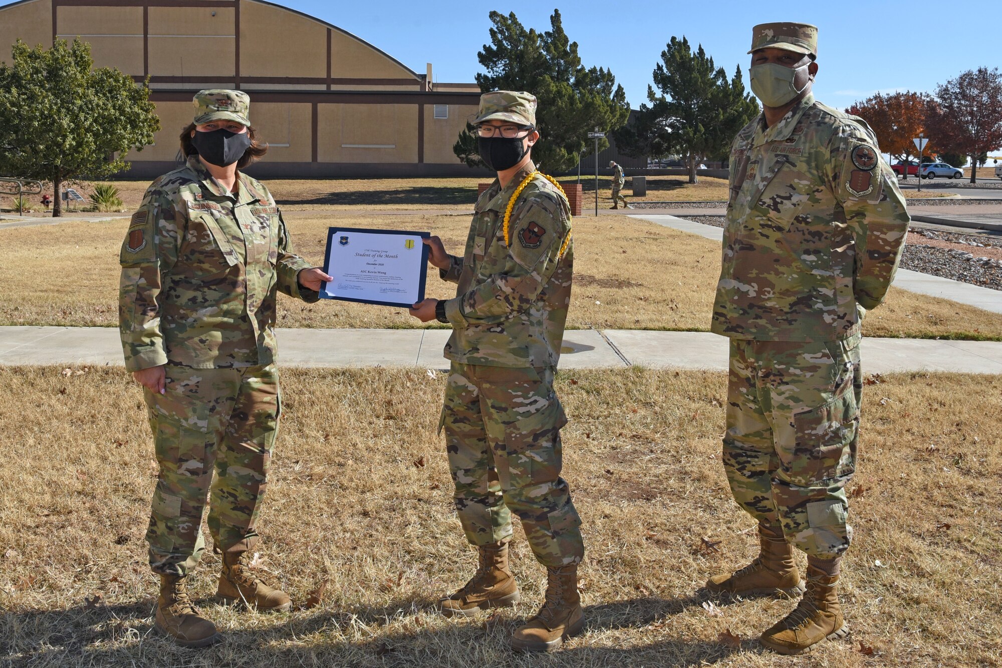 U.S. Air Force Col. Angelina Maguiness, 17th Training Group commander, presents Airman 1st Class Kevin Weng, 316th Training Squadron student, the 17th TRG Student of the Month award outside of the Brandenburg Hall on Goodfellow Air Force Base, Texas, Dec. 11, 2020. Weng worked hard for his award and had shown his dedication to his squadron and the training he received at Goodfellow. (U.S. Air Force photo by Senior Airman Abbey Rieves)