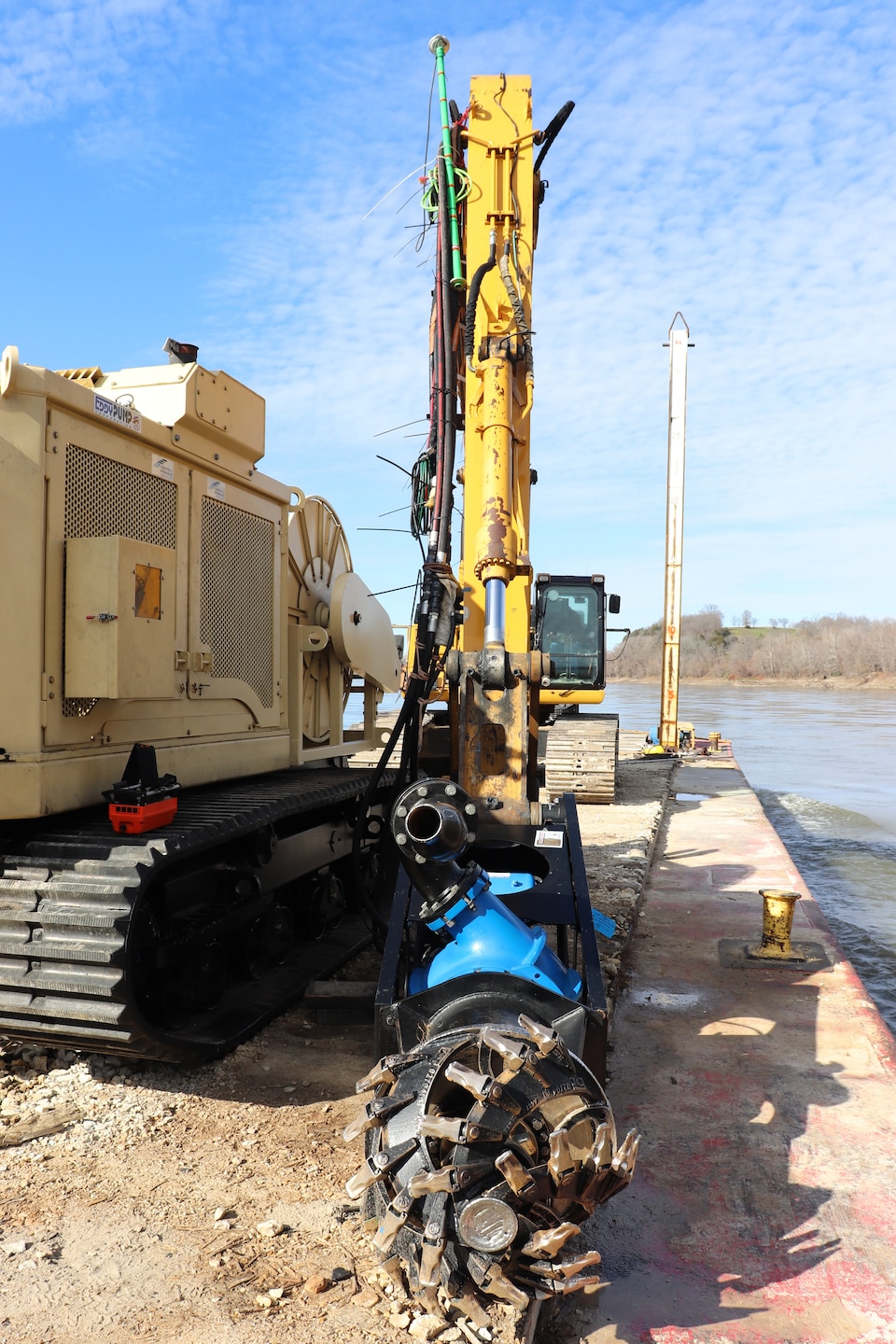 A Kansas City District track-hoe on a barge work boat took part in hydrodynamic dredging operations on the Missouri River November 11, 2020. The hydrodynamic dredge head is mounted on the bucket and the arm directs the flow the desired area of concern to be affected. The Engineering Research and Development Center brought the system to Kansas City District from Vicksburg, Miss., to assist in clearing shoals that developed on the Missouri River due to damages from flooding to the river control structures. The device enabled the combined team to redirect sandy material back into suspension in the current of the river and away from the built-up areas that impede navigation on the river.
