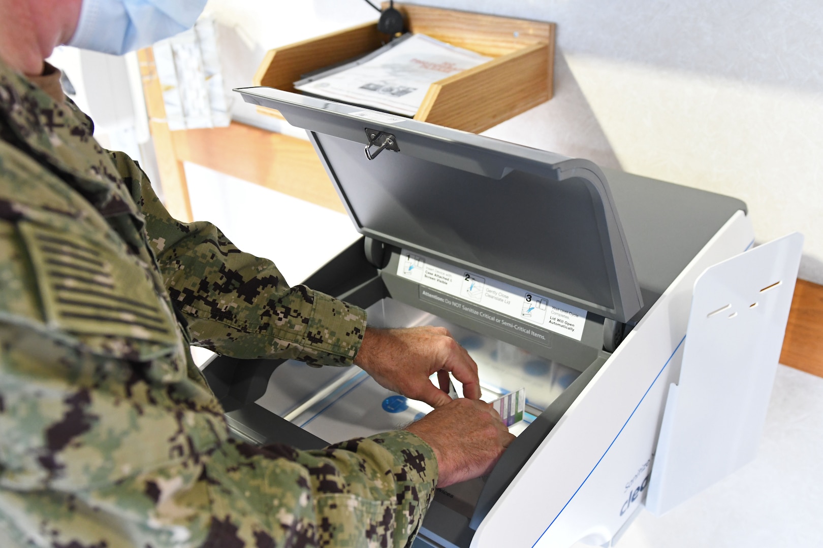 Officer puts keys and badges in UV sanitation machine.