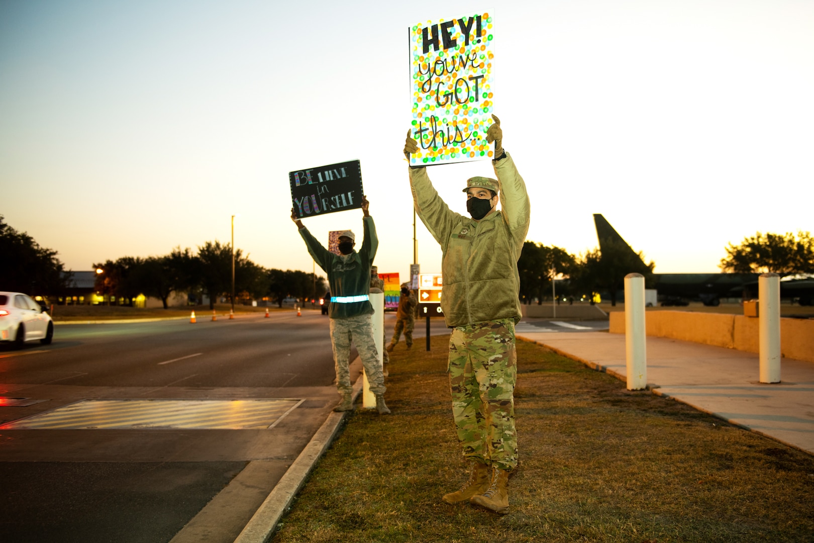 U.S. Air Force Master Sgt. Milton White (right), 616th Operations Center, and Master Sgt. Evans Opoku, Air Force Medical Readiness Agency, hold signs to spread holiday cheer for drivers to see Dec. 18, 2020, at Joint Base San Antonio-Lackland, Texas.