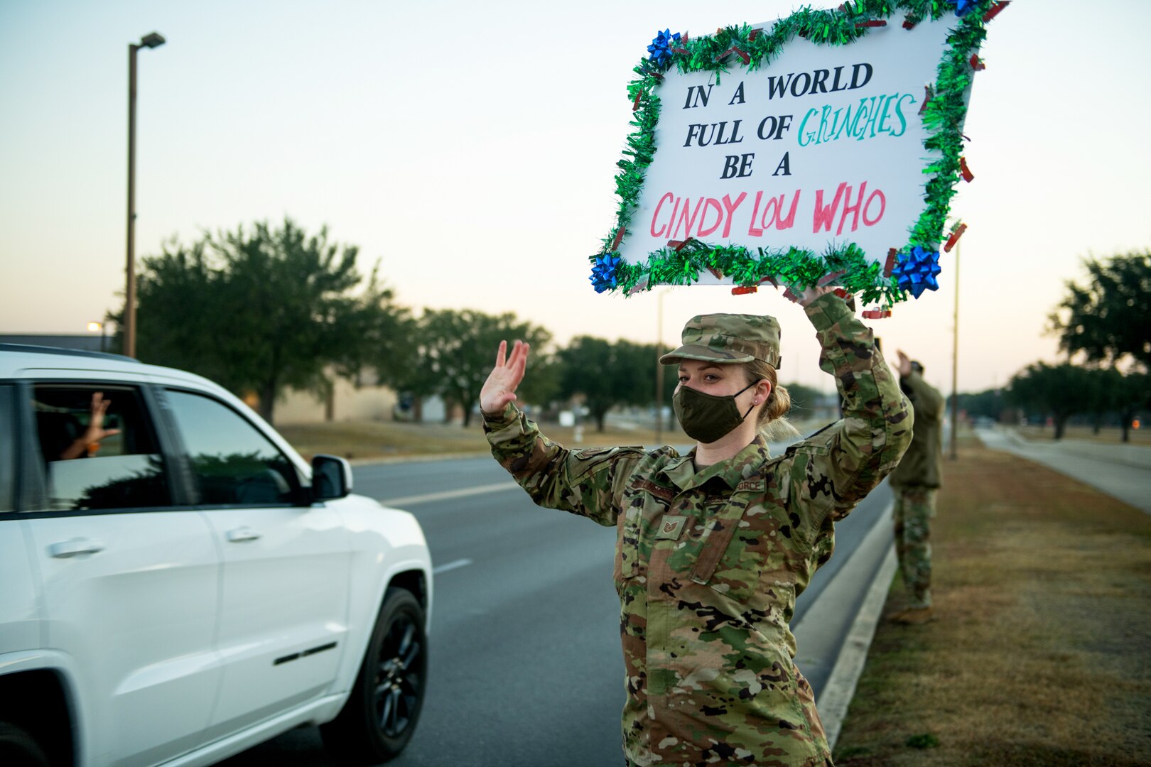 U.S. Air Force Tech. Sgt. Cassandra Elchelberger, Air Force Services Center, holds signs to spread holiday cheer for drivers to see Dec. 18, 2020, at Joint Base San Antonio-Lackland, Texas.