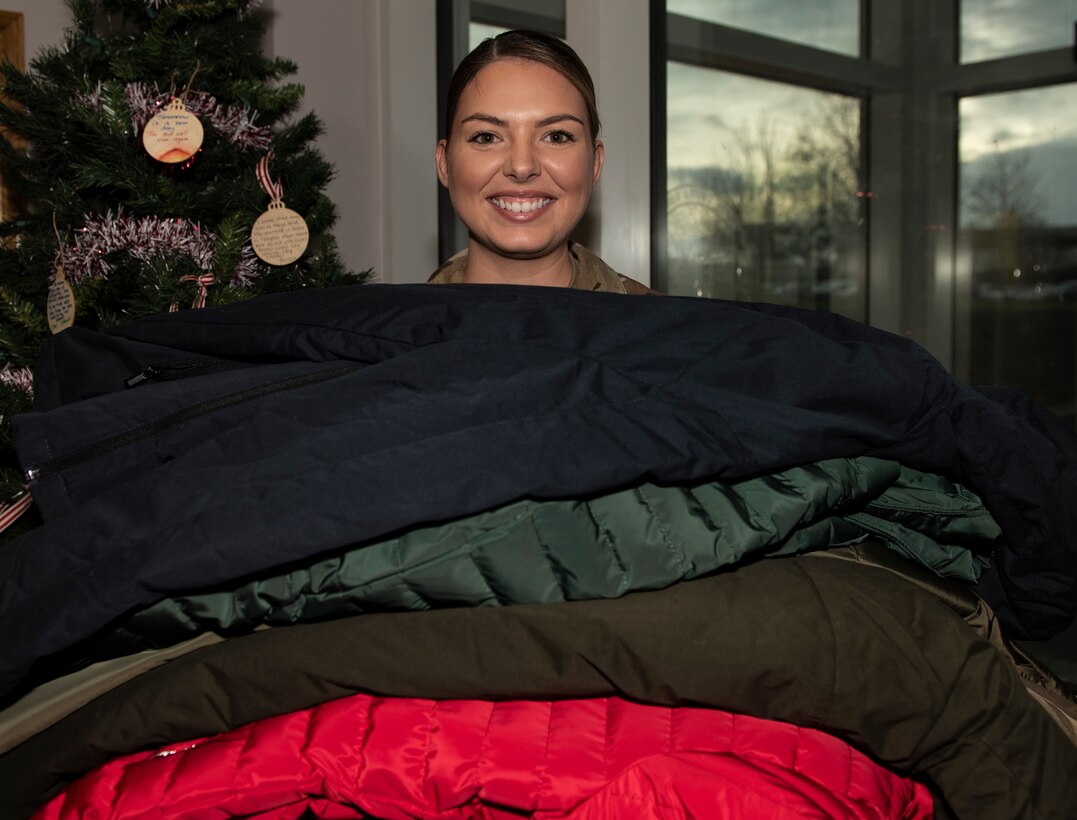 U.S. Air Force Senior Airman Vanessa Costello, 48th Communications Squadron booster club president, holds a stack of brand new coats that have been donated at Royal Air Force Lakenheath, England, Dec. 16, 2020. The 48th CS organized the clothing drive in support of a local community homeless shelter in the hopes of bringing a little bit more joy into the holiday season. (U.S. Air Force photo by Airman 1st Class Jessi Monte)