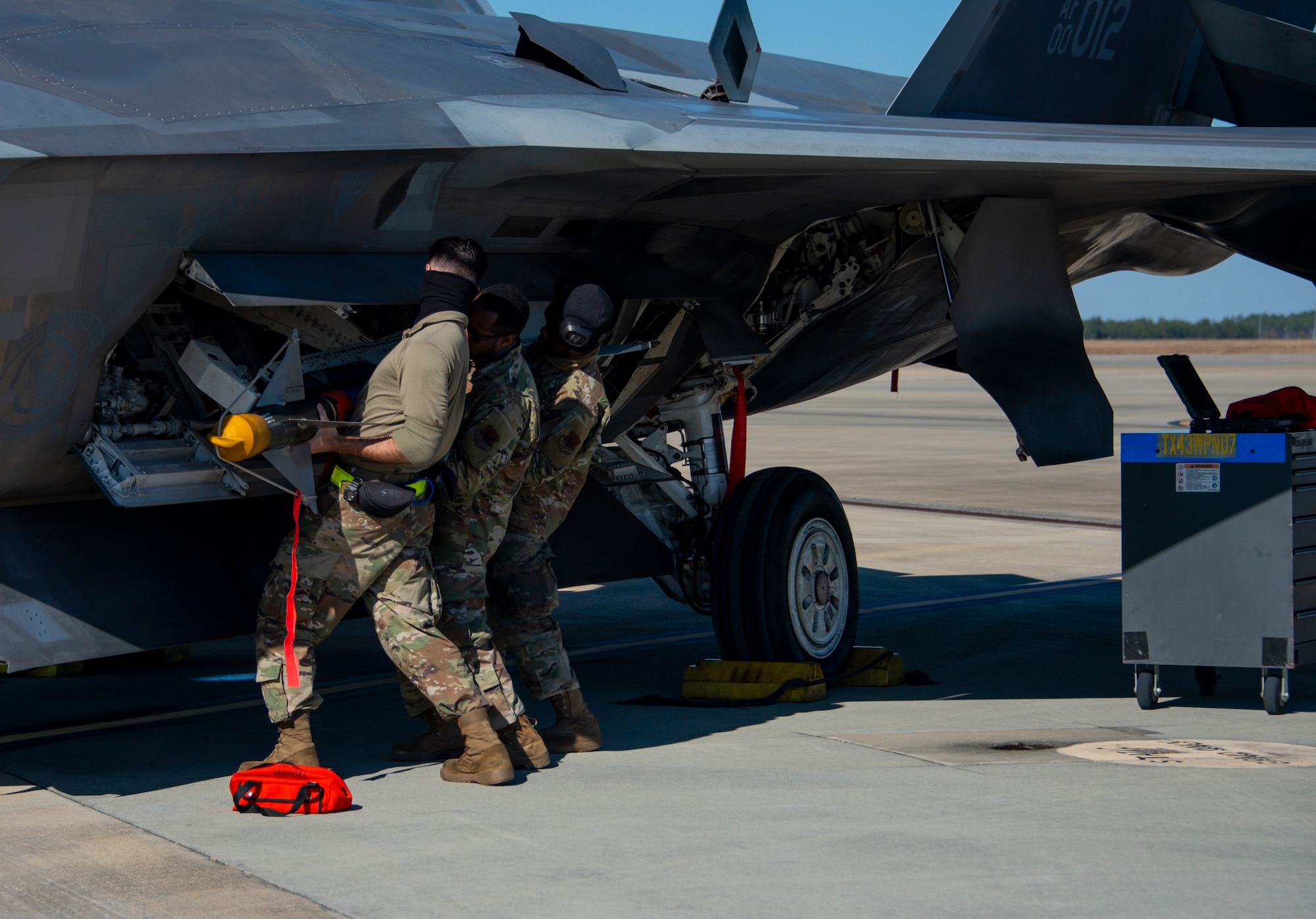 men load missile onto an F-22