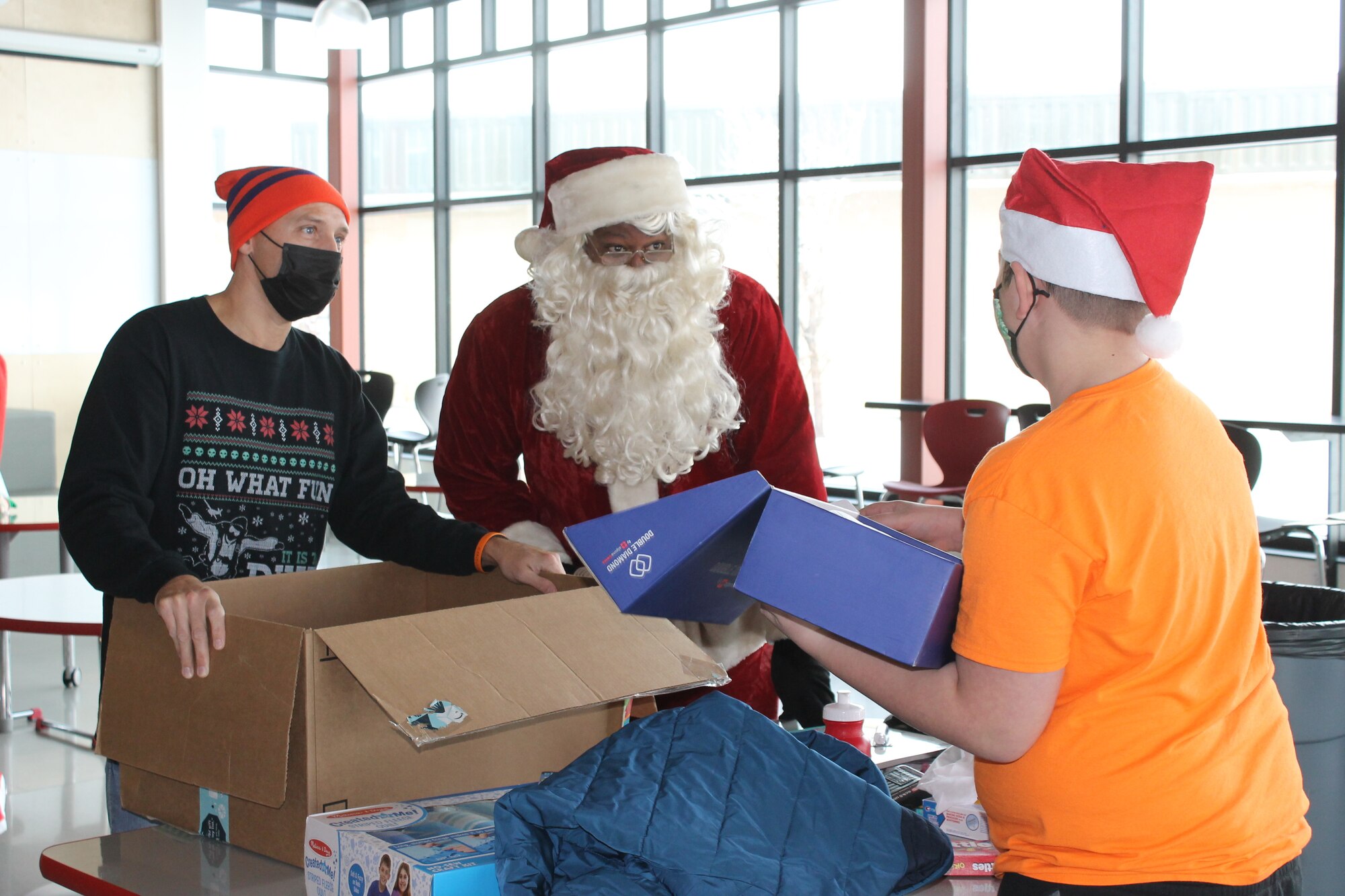 Master Sgt. David McAlhany, a reservist in the 67th Aerial Port Squadron, along with Santa Claus, cheers on Taelon, a student at Mound Fort Junior High, as he opens gifts during a Christmas party hosted Dec. 18 by past and present Airmen in the 67th APS.