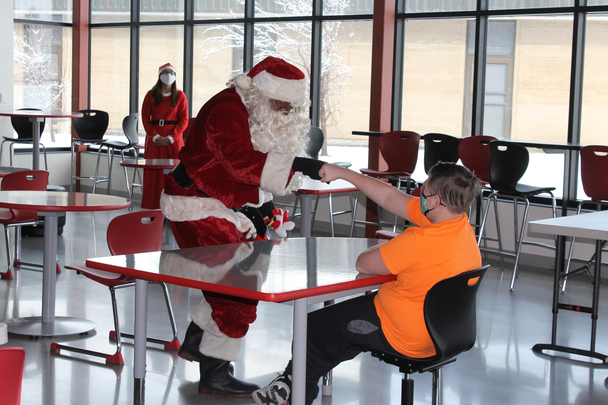 Santa Claus fist bumps Taelon, a student at Mound Fort Junior High, during the Christmas party hosted Dec. 18 by Airmen from the wing’s 67th Aerial Port Squadron.