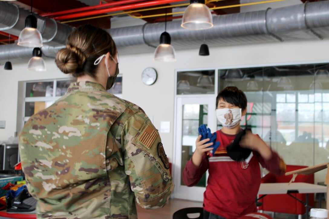 Senior Airman Amy Barnes, a reservist in the 67th Aerial Port Squadron, helps Shaylan open gifts during a Christmas party Dec. 18 for students with special needs.