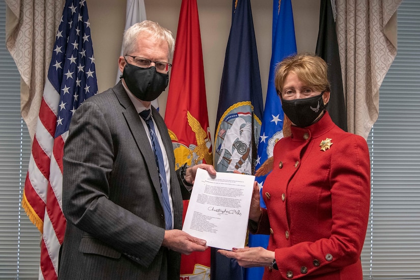 A man and a woman pose with a signed document.