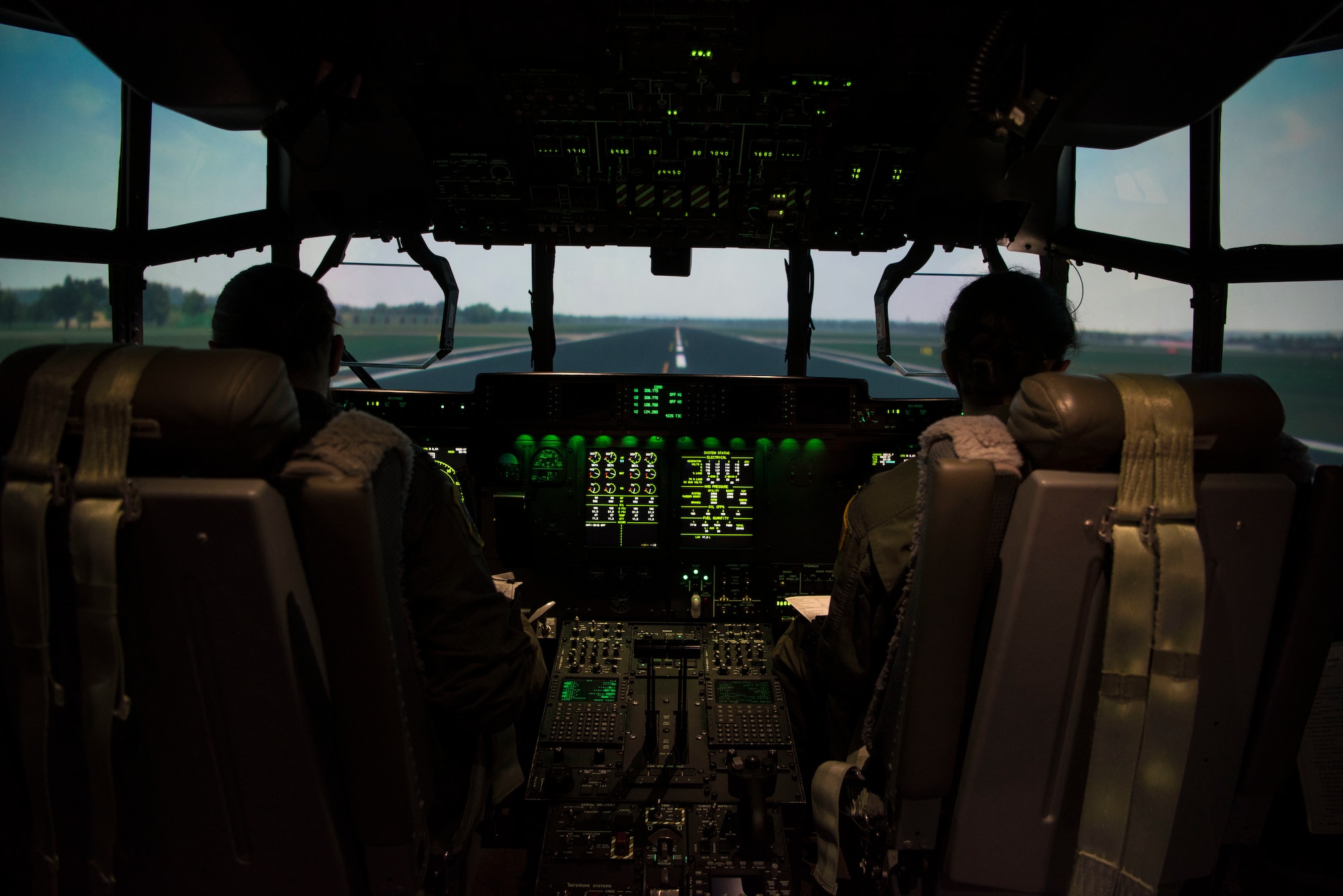 Two people in the cockpit of a C-130 simulator.