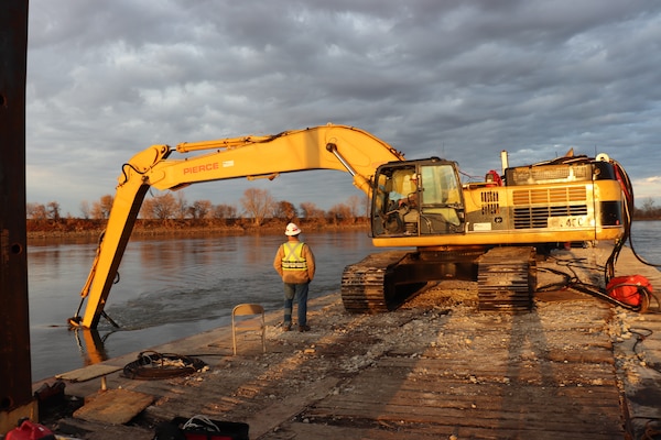 A Kansas City District track-hoe on a barge work boat took part in hydrodynamic dredging operations on the Missouri River November 11, 2020. The hydrodynamic dredge head is mounted on the bucket and the arm directs the flow the desired area of concern to be affected. The Engineering Research and Development Center brought the system to Kansas City District from Vicksburg, Miss., to assist in clearing shoals that developed on the Missouri River due to damages from flooding to the river control structures. The device enabled the combined team to redirect sandy material back into suspension in the current of the river and away from the built-up areas that impede navigation on the river.
