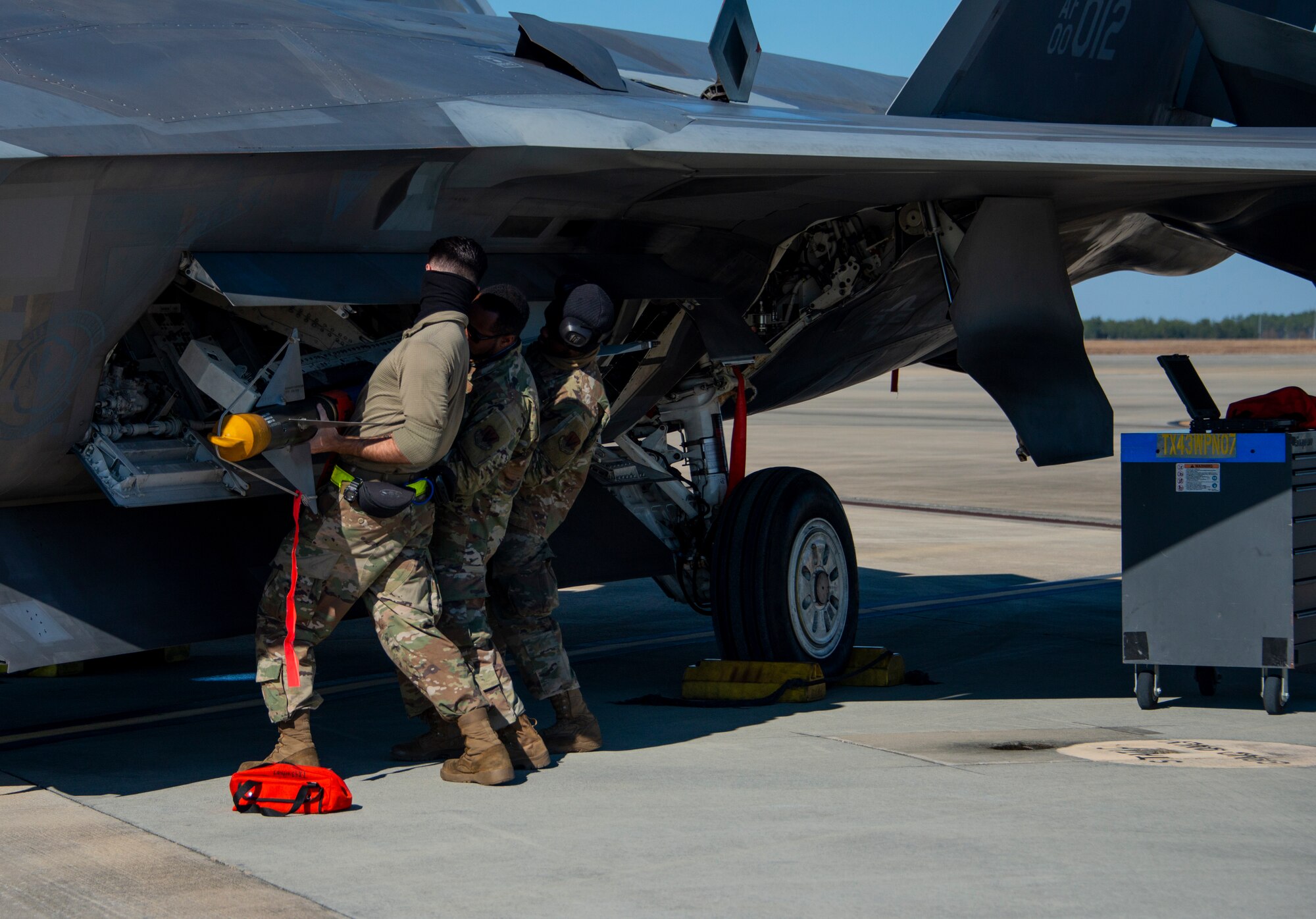 men load missile onto an F-22