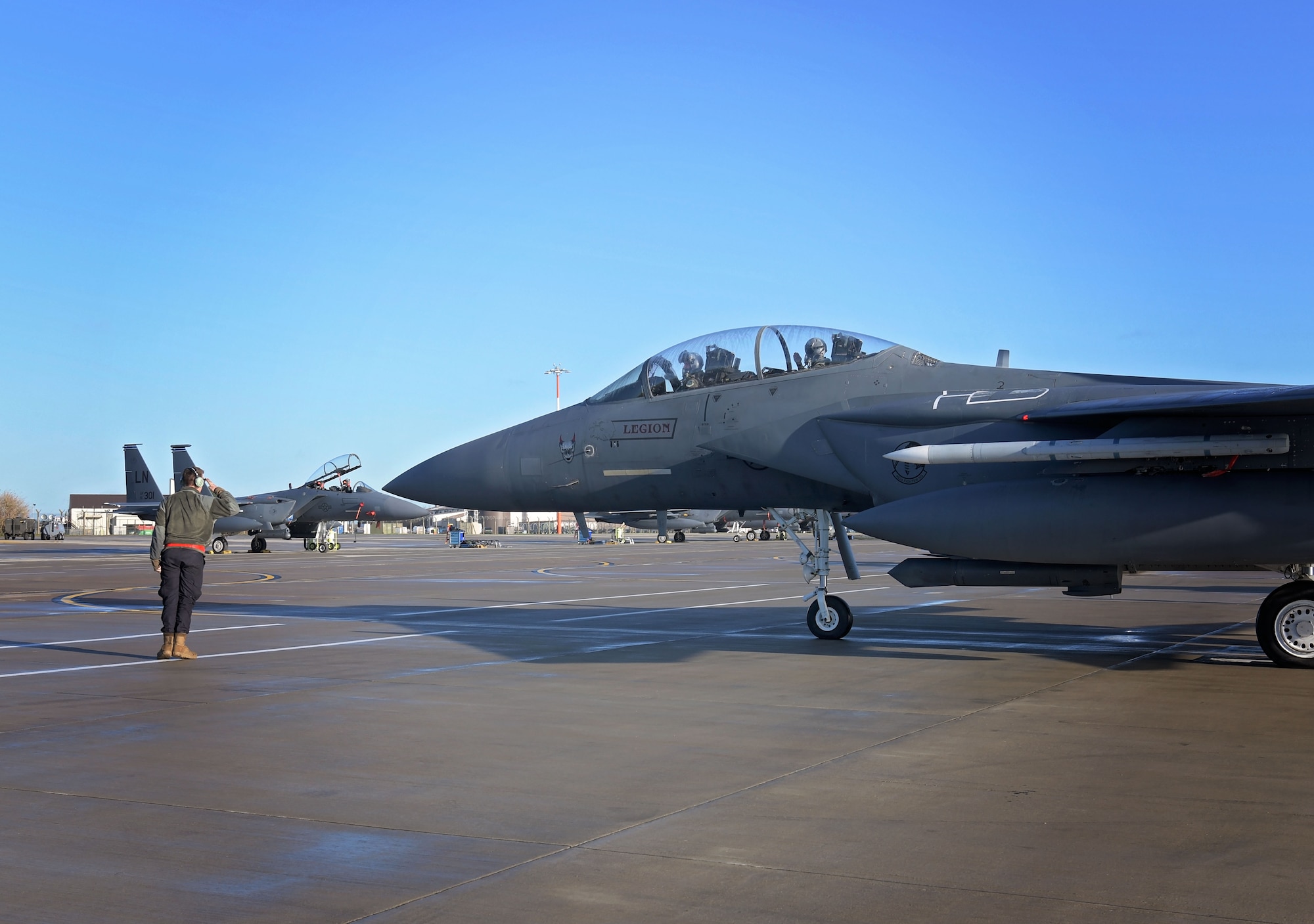 A crew chief assigned to the 494th Aircraft Maintenance Unit marshalls an F-15E Strike eagle carrying U.S. Air Force Capt. Woodruff Johnson, 494th Fighter Squadron weapons officer and recipient of  the USAF Weapons School Robbie Risner Award, at Royal Air Force Lakenheath, England, Dec. 17, 2020. Johnson, among 123 graduates, completed 380 hours each and 21 combat missions that tested his strategic warfighting capabilities. (U.S. Air Force photo by Senior Airman Shanice Ship)