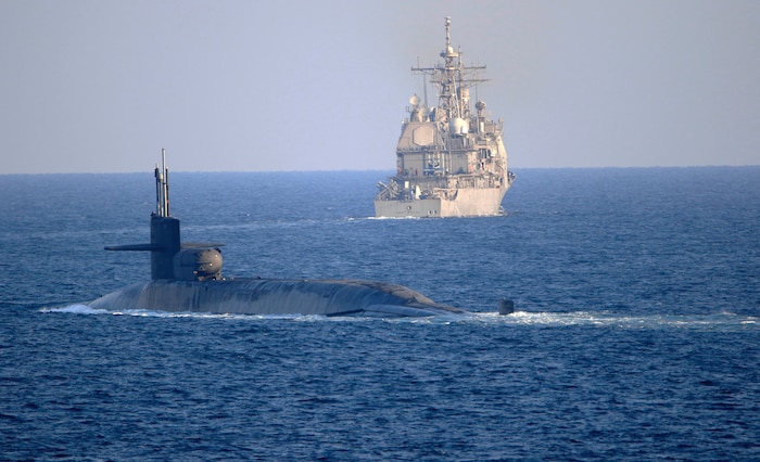 The guided-missile submarine USS Georgia (SSGN 729), front, transits the Strait of Hormuz with the guided-missile cruiser USS Port Royal (CG 73) and the guided-missile cruiser USS Philippine Sea (CG 58), not pictured, Dec. 21. Georgia is deployed to the U.S. 5th Fleet area of operations in support of naval operations to ensure maritime stability and security in the Central Region, connecting the Mediterranean and Pacific through the Western Indian Ocean and three critical chokepoints to the free flow of global commerce.