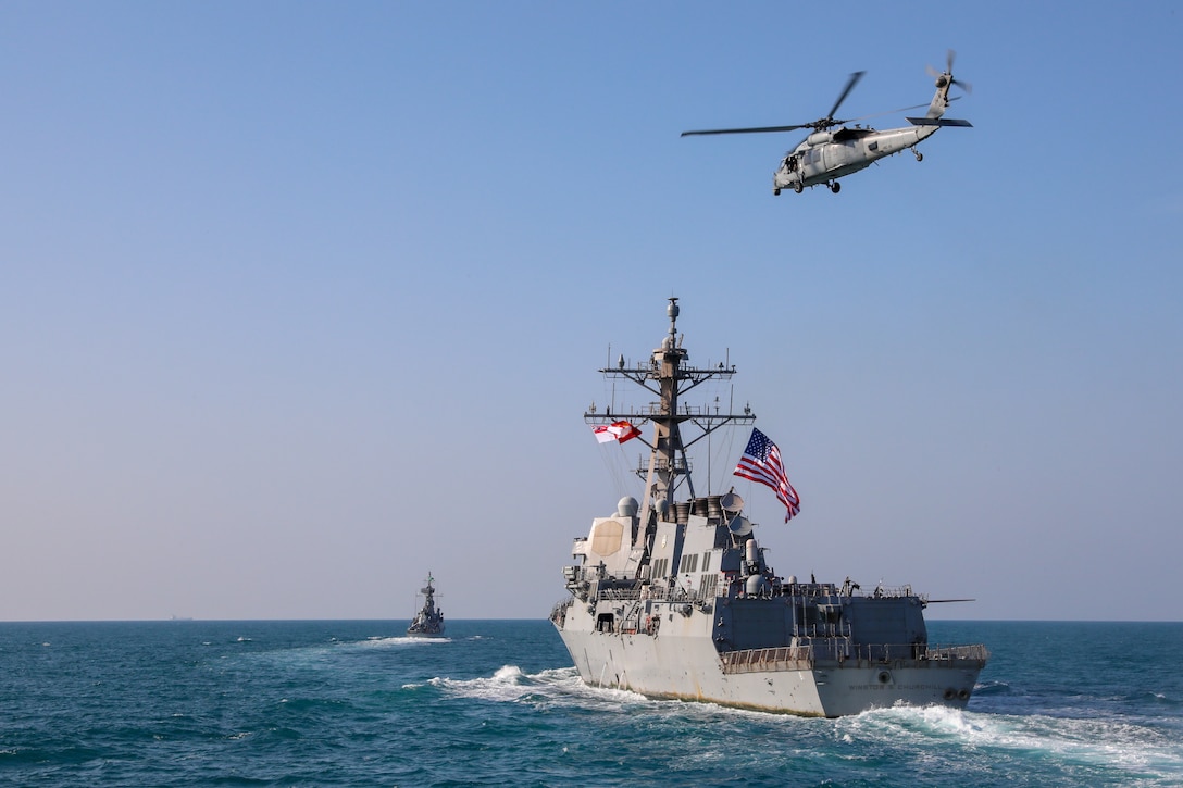 Royal Saudi Naval Force corvette HMS Badr (612), left, and the guided-missile destroyer USS Winston S. Churchill (DDG 81) transit the Arabian Gulf with a U.S. Navy MH-60R Sea Hawk helicopter during a joint and combined air operations in support of maritime surface warfare (AOMSW) exercise in the Arabian Gulf, Dec. 18. Combined integration operations between joint U.S. forces are regularly held to maintain interoperability and the capability to counter threats posed in the maritime domain, ensuring freedom of navigation and free flow of commerce throughout the region's heavily trafficked waterways.