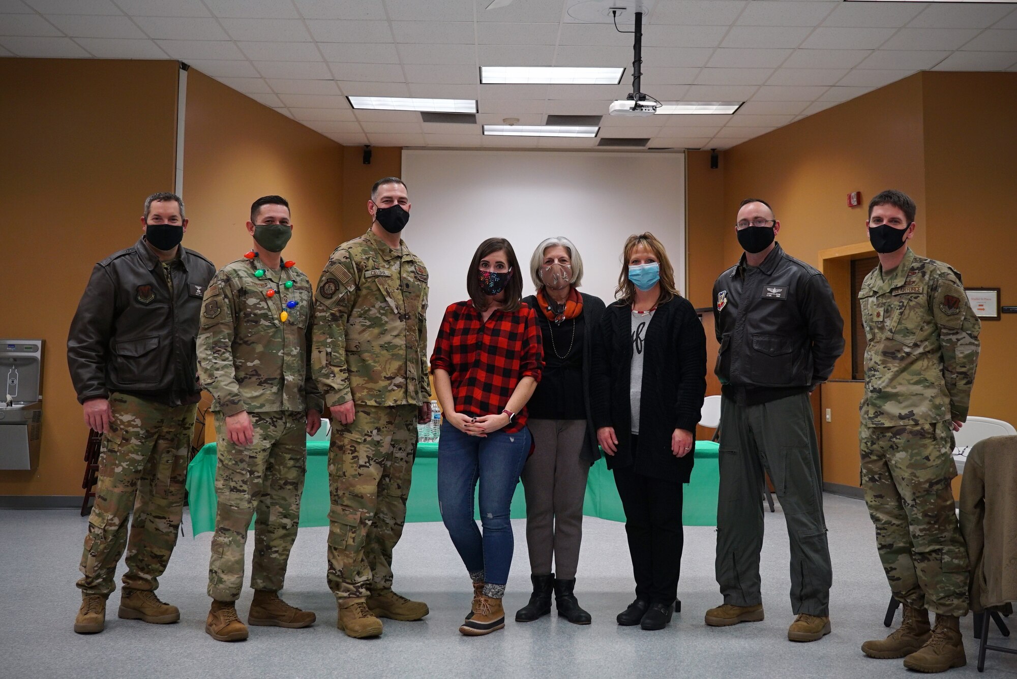 Eight adults pose standing shoulder-to-shoulder for a photo.