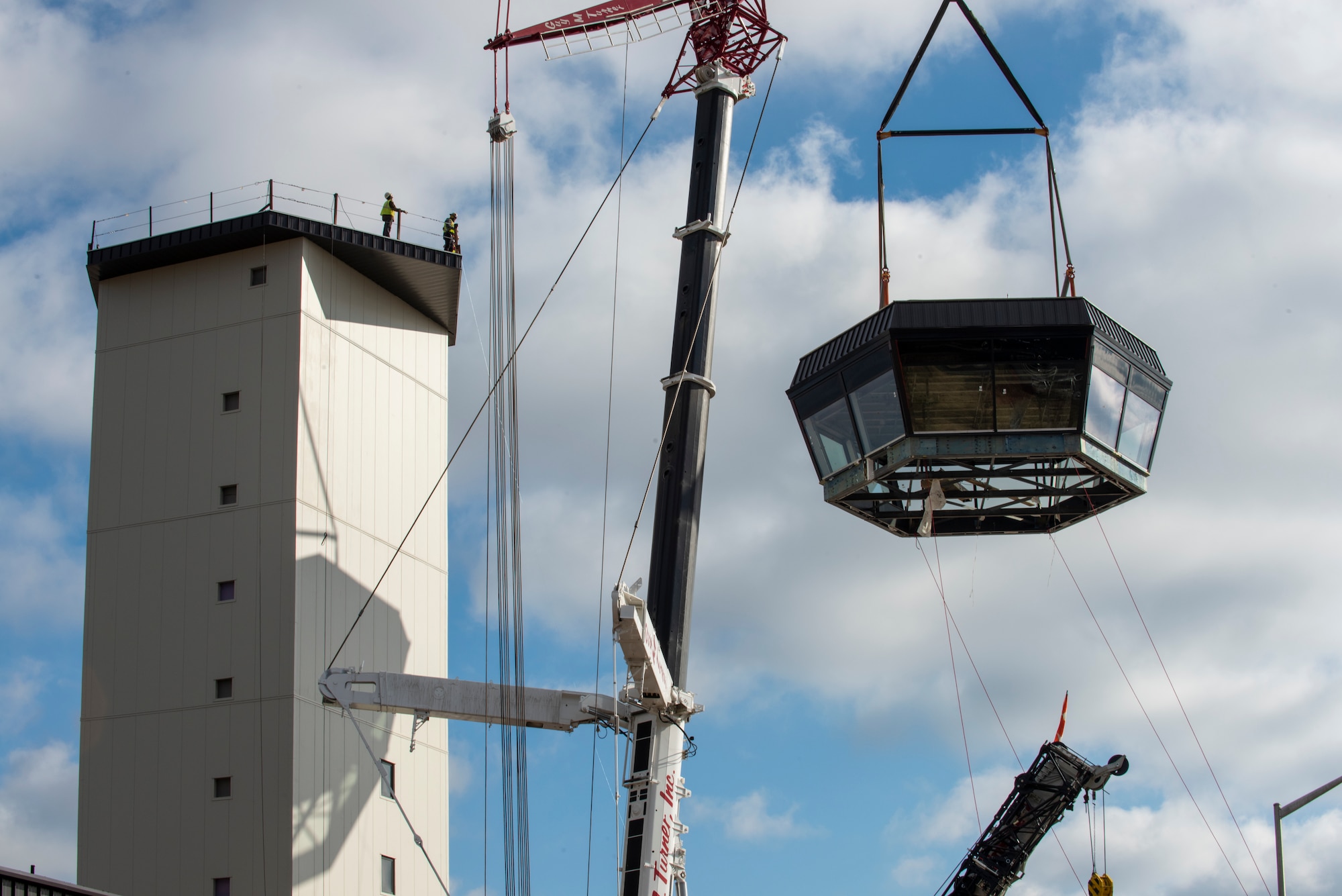 The control cab is hoisted in the air by a crane to be placed atop of the new air traffic control tower at Seymour Johnson Air Force Base, North Carolina.