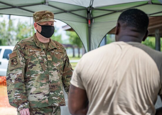 Photo of an Airmen standing in front of a flag background