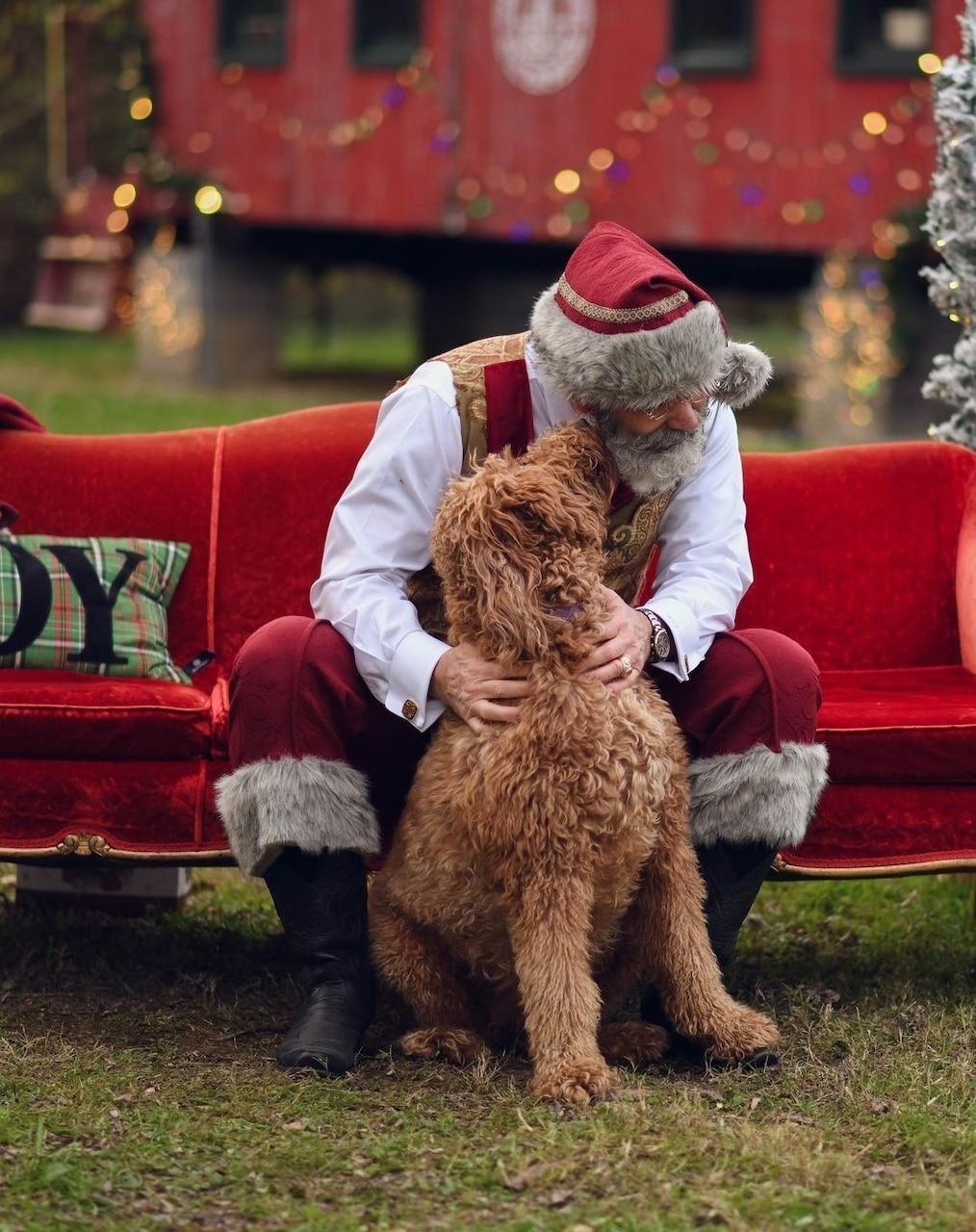 Santa plays with a dog.