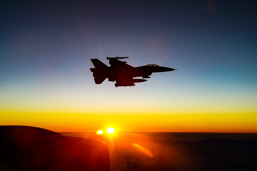 A fighter jet flies through the sky at twilight.