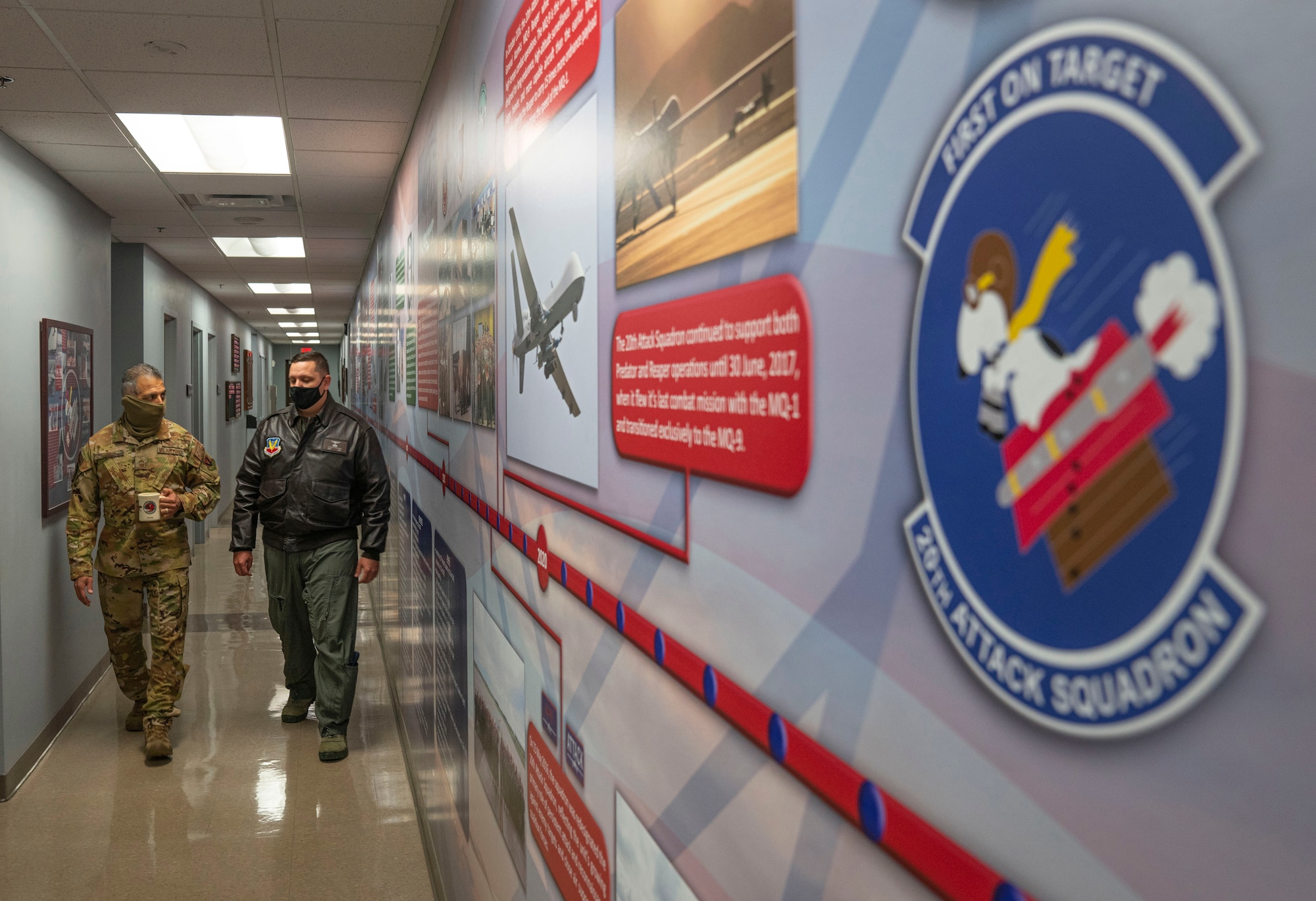 Two Airmen walk down a hallway inside the 20th Attack Squadron.