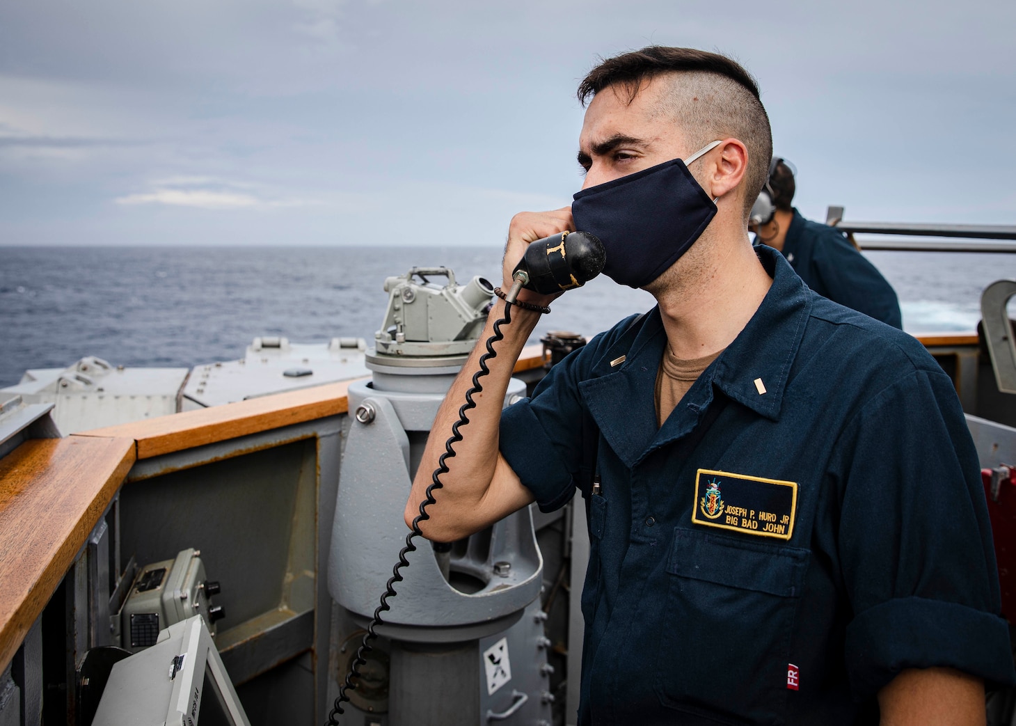 SOUTH CHINA SEA (Dec. 22, 2020) Conning Officer Ensign Joseph Hurd, from Foley, Alabama, gives course and speed orders to the helm while standing watch on the bridge wing as the guided-missile destroyer USS John S. McCain (DDG 56) conducts routine underway operations. McCain is forward-deployed to the U.S. 7th Fleet area of operations in support of security and stability in the Indo-Pacific region. (U.S. Navy photo by Mass Communication Specialist 2nd Class Markus Castaneda)