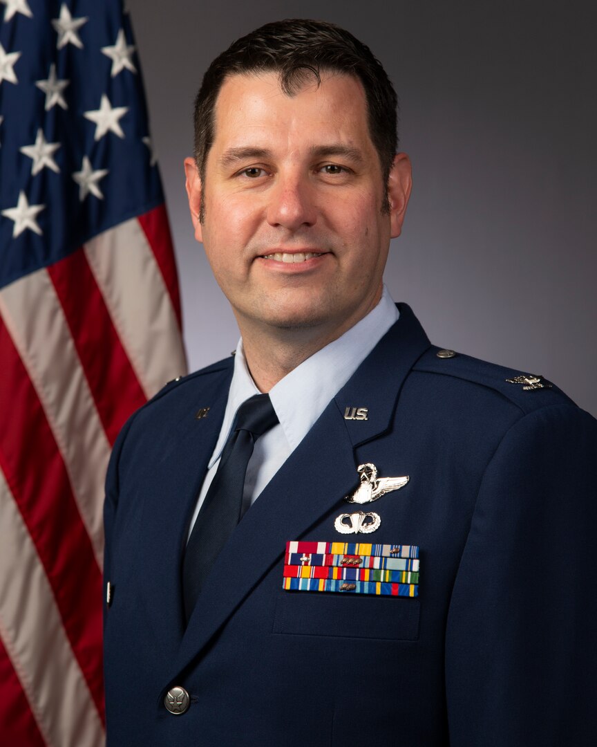 An Airman wearing his blues smiles for an official military photo