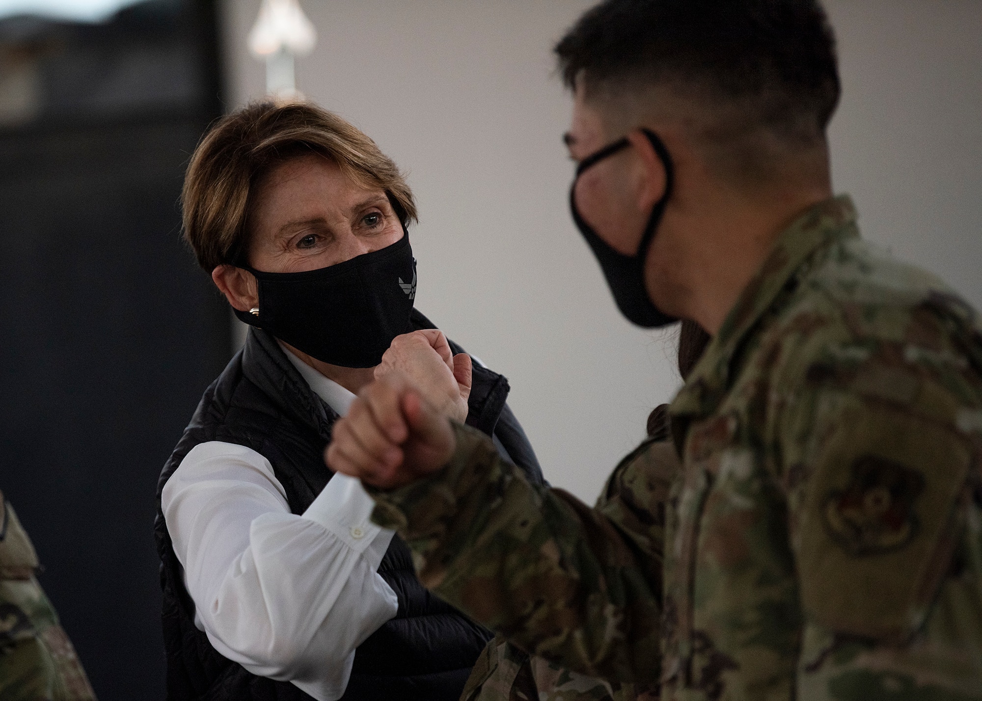 Secretary of the Air Force Barbara Barrett bumps elbows with an Airman assigned to the 380th Air Expeditionary Wing during a visit to Al Dhafra Air Base, United Arab Emirates, Dec. 21, 2020.