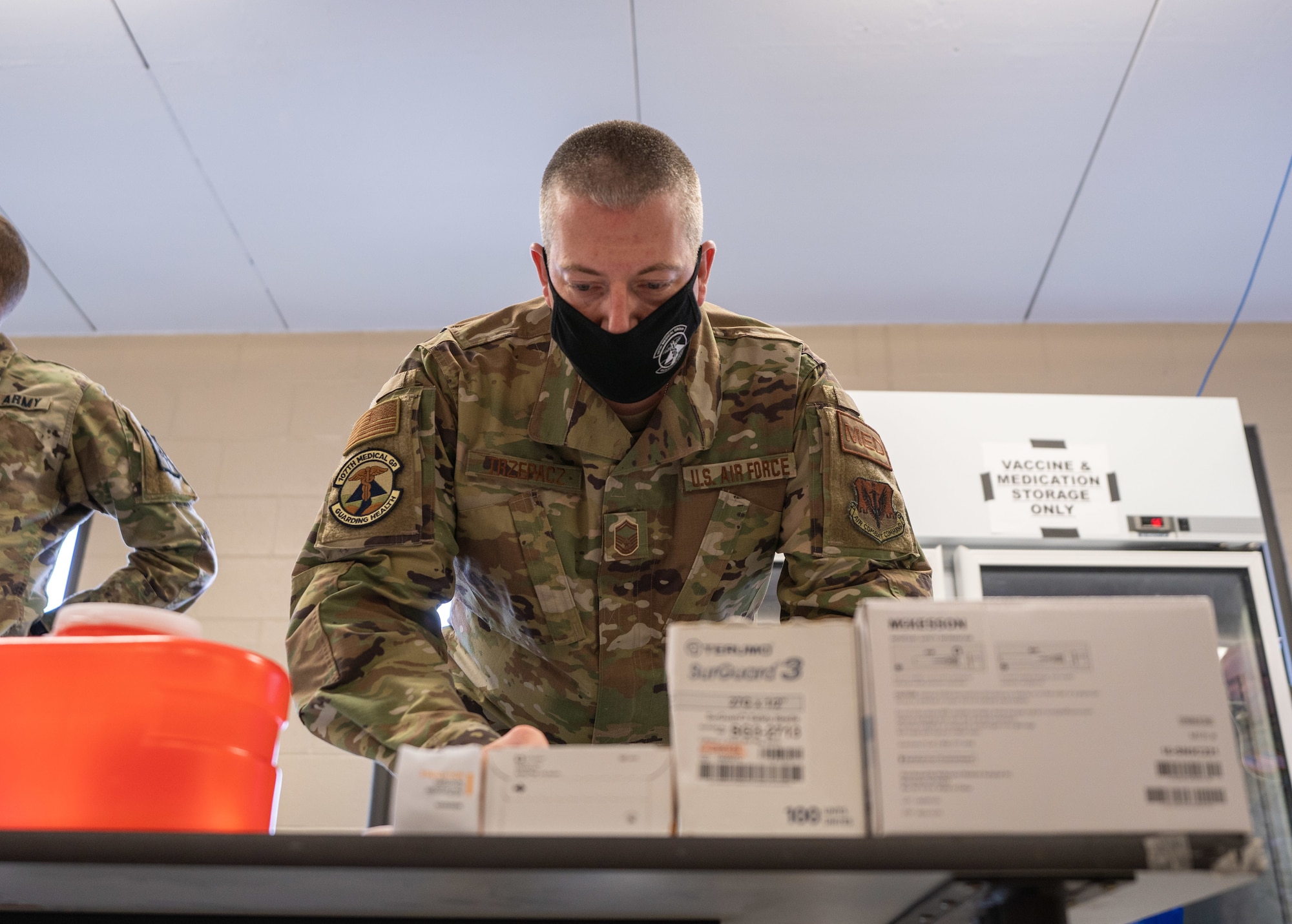 U.S. Air Force Senior Master Sgt. Donald Trzepacz, assigned to Joint Task Force COVID-19, New York National Guard, prepares the COVID-19 vaccination area at the Camp Smith Training Site Medical Readiness Clinic, N.Y., on December 16, 2020. The New York National Guard is participating in a Department of Defense vaccine pilot program in which 44,000 doses of the Pfizer vaccine are being administered to front line medical personnel at 16 locations around the world. (U.S. Army National Guard photo by Sgt. Sebastian Rothwyn)