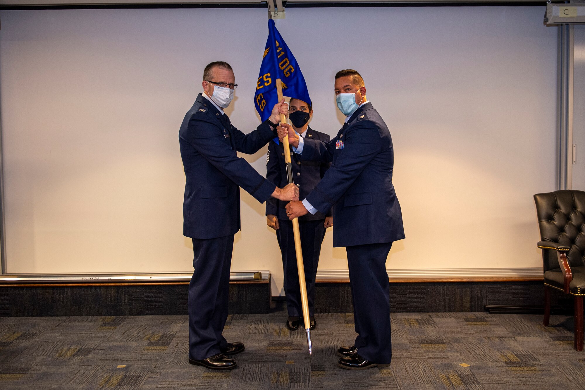 Col. Gregory Buchanan, 911th Airlift Wing Operations Group commander, passes a guidon to incoming 911th Aeromedical Staging Squadron Commander Lt. Col. Gregory S. Sell during an assumption of command ceremony at the Pittsburgh International Airport Air Reserve Station, Pennsylvania, Nov. 8, 2020.