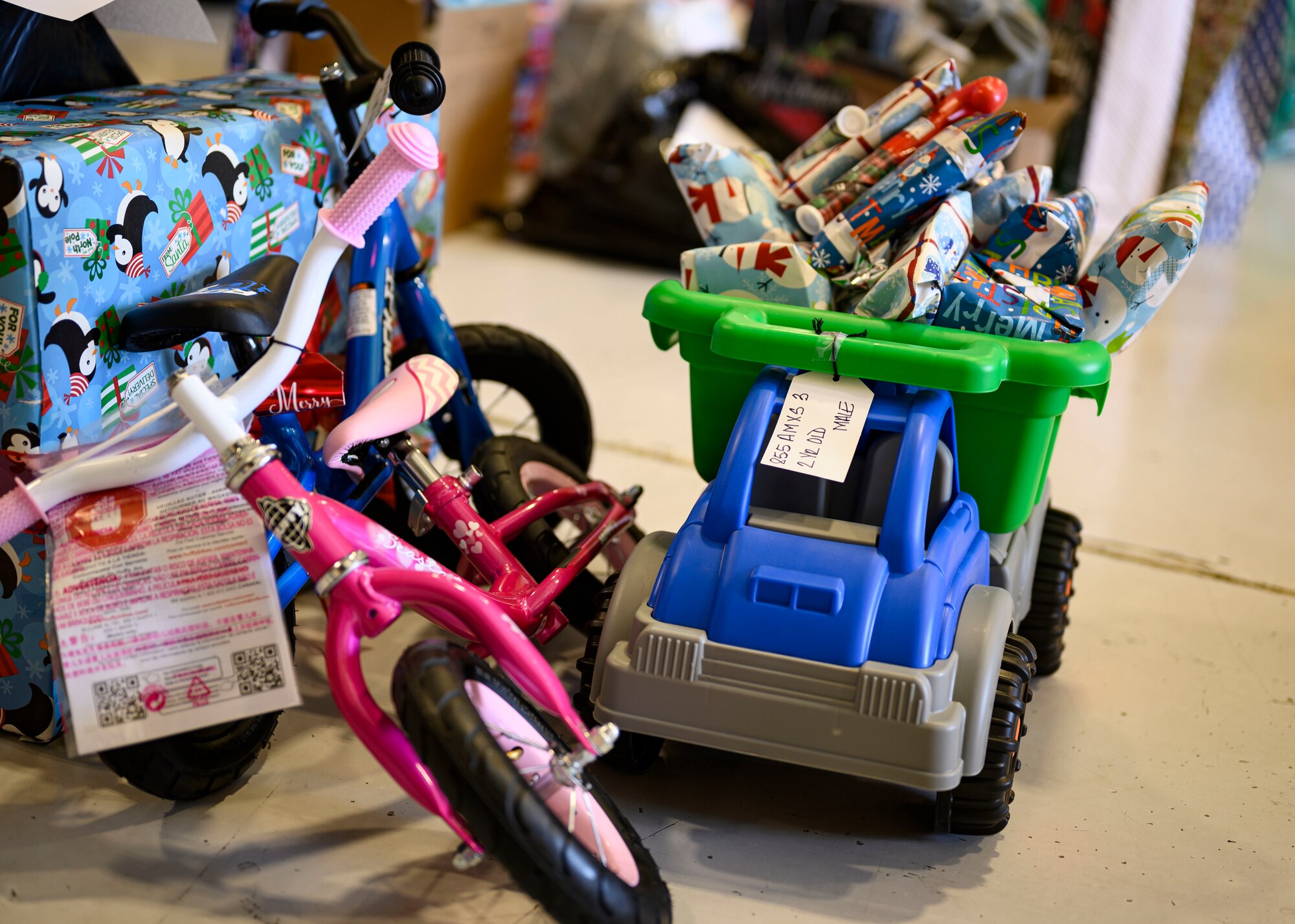 a pink bike and blue toy dump truck loaded with wrapped gifts