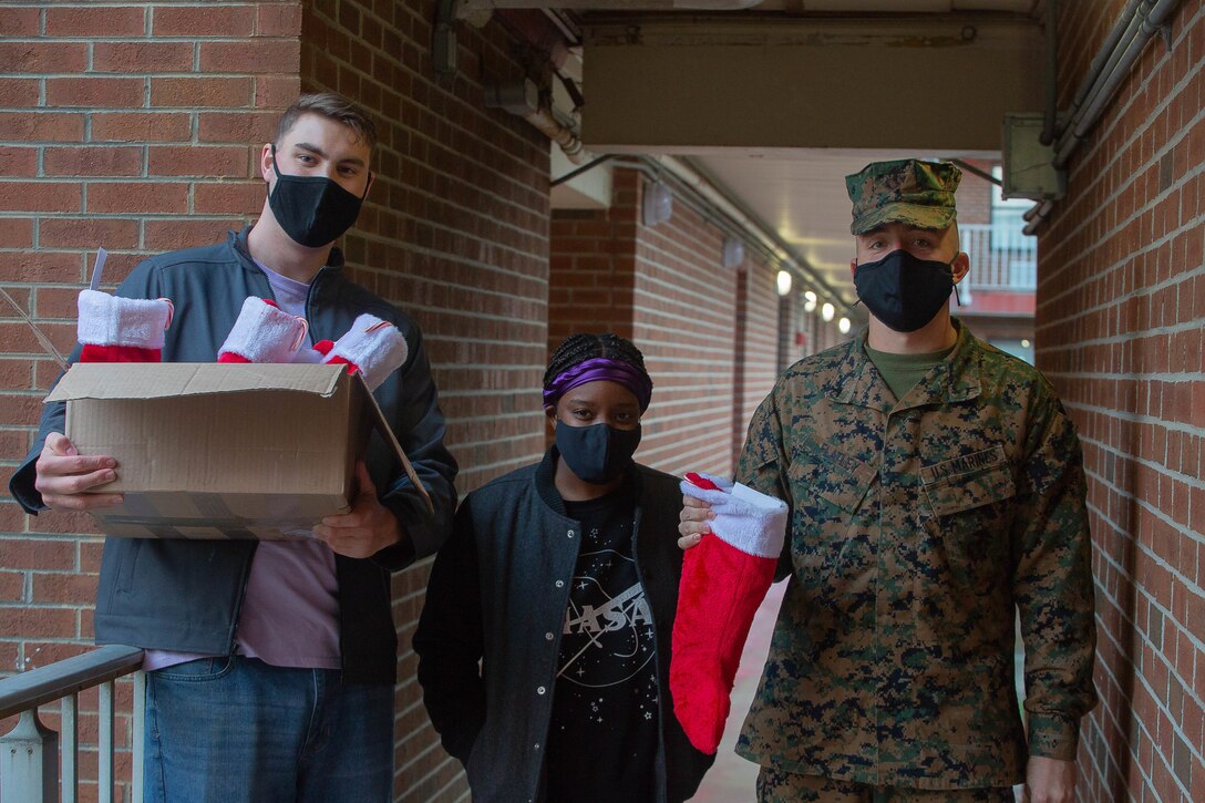U.S. Marine Corps Cpl. Spencer Sargeant, an intel analyst, left, Lance Cpl. Jazzmyne Meadows, a logistic embarkation specialist, middle, and Pfc. Brendan Flatley, a Marine Air Ground Task Force planner with Headquarters and Service Battalion, U.S. Marine Corps Forces Command, Fleet Marine Force Atlantic, deliver stuffed stockings to Marines living in the barracks at Camp Elmore, Norfolk, Virginia, Dec. 21, 2020. The Marines on Camp Elmore received holiday stockings from the Daughters of the American Revolution association and from the families of service members. (U.S. Marine Corps photos by Cpl. Danielle Abshire/released)