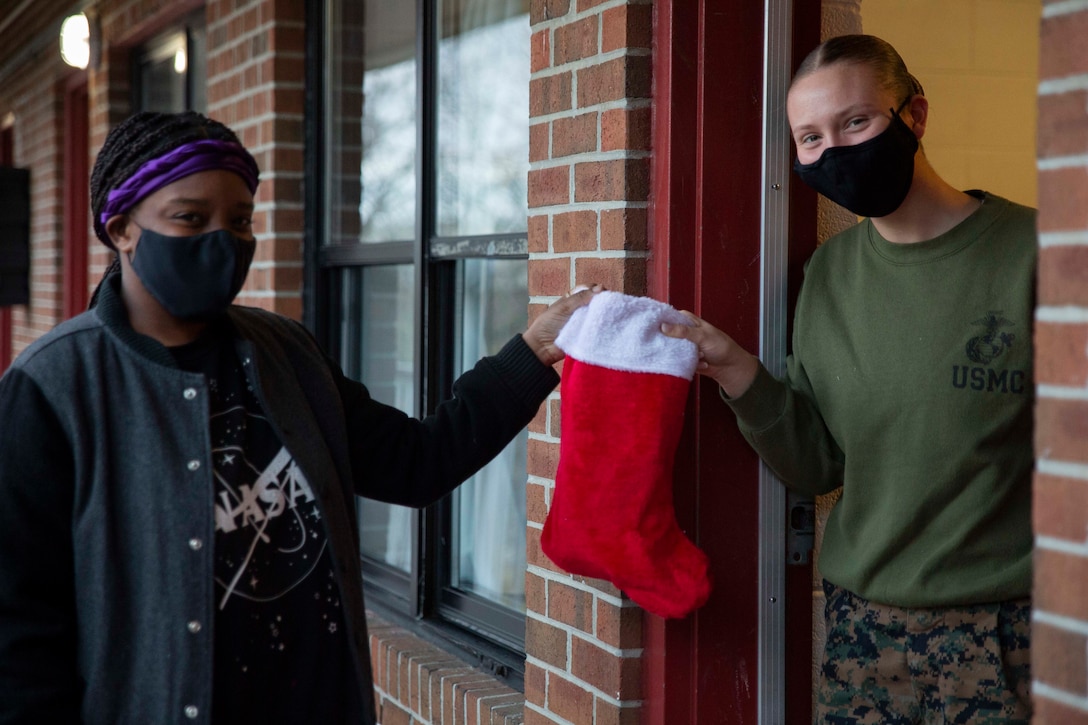 U.S. Marine Corps Pfc. Jazzmyn Meadows, an embarkation specialist with U.S. Marine Corps Forces Command, Fleet Marine Force Atlantic, hands Pfc. Tia Bastian, a Marine Air Ground Task Force Planner with U.S. Marine Corps Forces Command, Fleet Marine Force Atlantic a stocking Dec. 21, 2020, on Camp Elmore, Norfolk, Virginia. The Marines on Camp Elmore received holiday stockings from the Daughters of the American Revolution association and from the families of service members. (U.S. Marine Corps photo by Sgt. Desmond Martin/released)