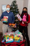 PORTSMOUTH, Va. (Dec. 21, 2020) Ensign Andolyn Medina, Operation Peace founder, poses for a photo with Chris Brogan, NMCP’s child life specialist, and the many of the gifts donated to children of Naval Medical Center Portsmouth’s (NMCP) Pediatric Inpatient Wards.