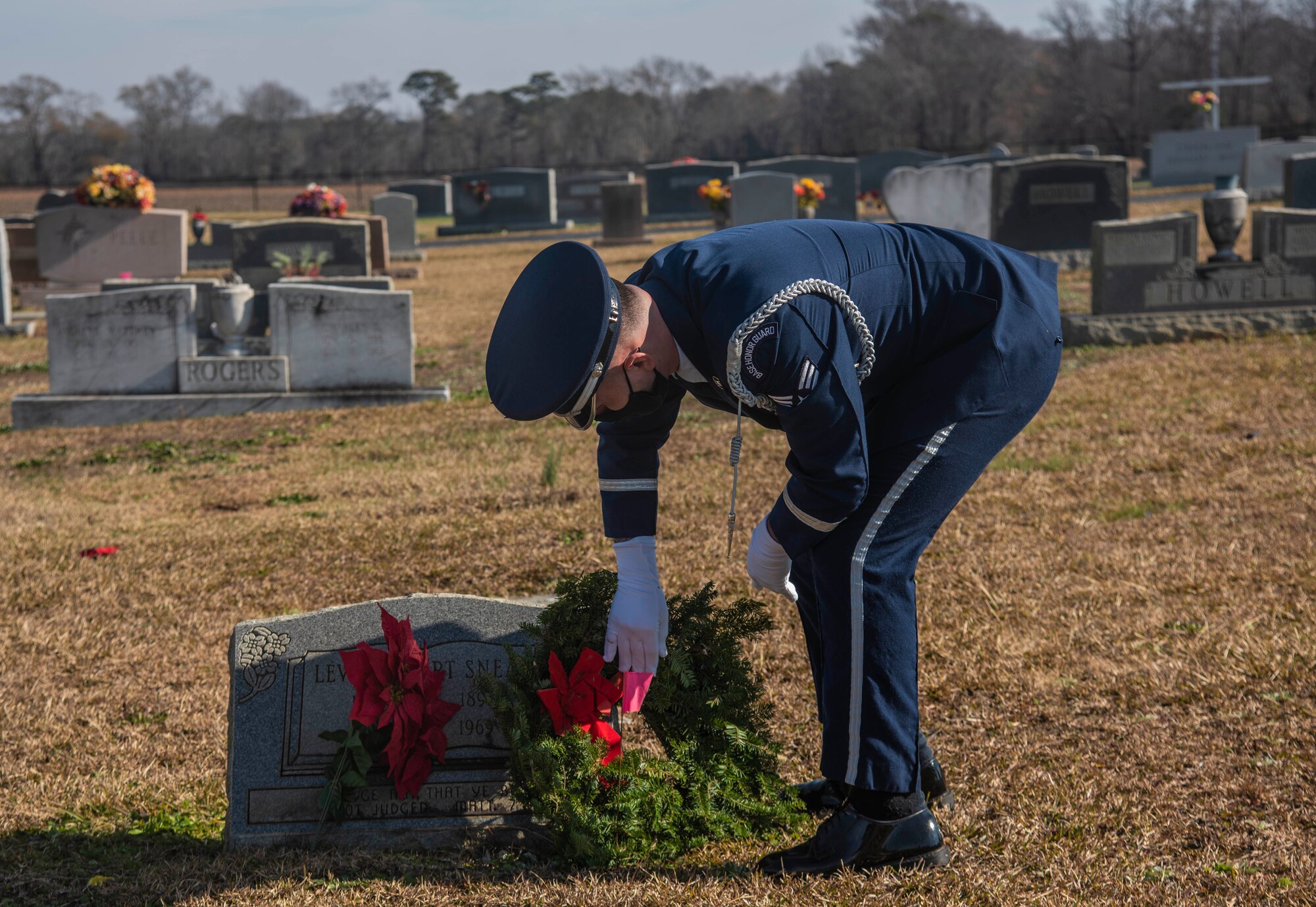 An Airmen places a Christmas wreath on a veteran's grave during the Wreaths Across America event.