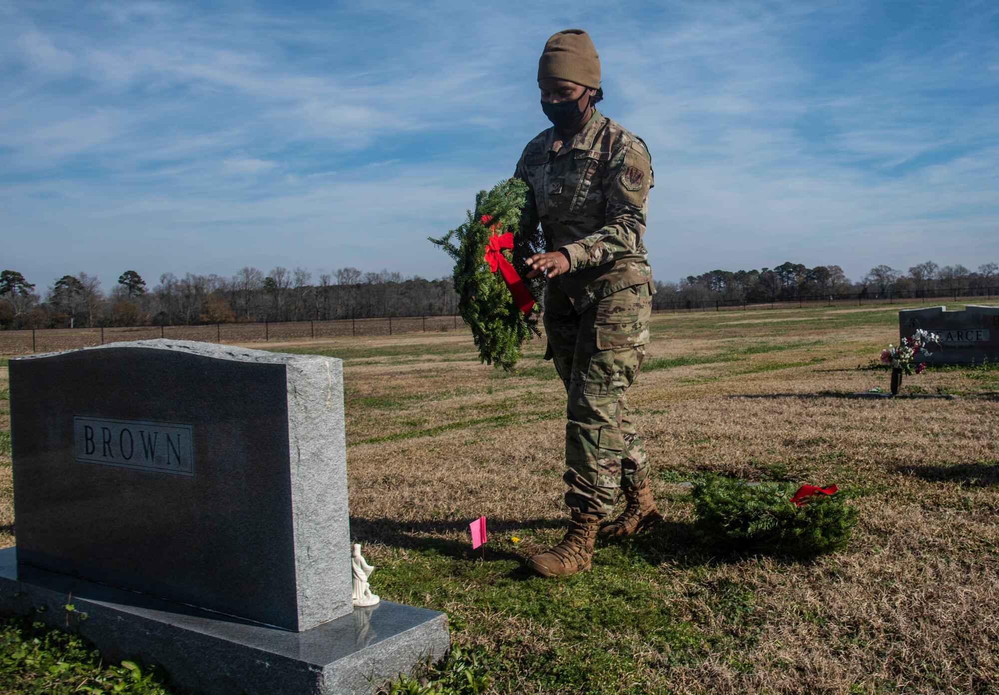 An Airmen places a Christmas wreath on a veteran's grave during the Wreaths Across America event.