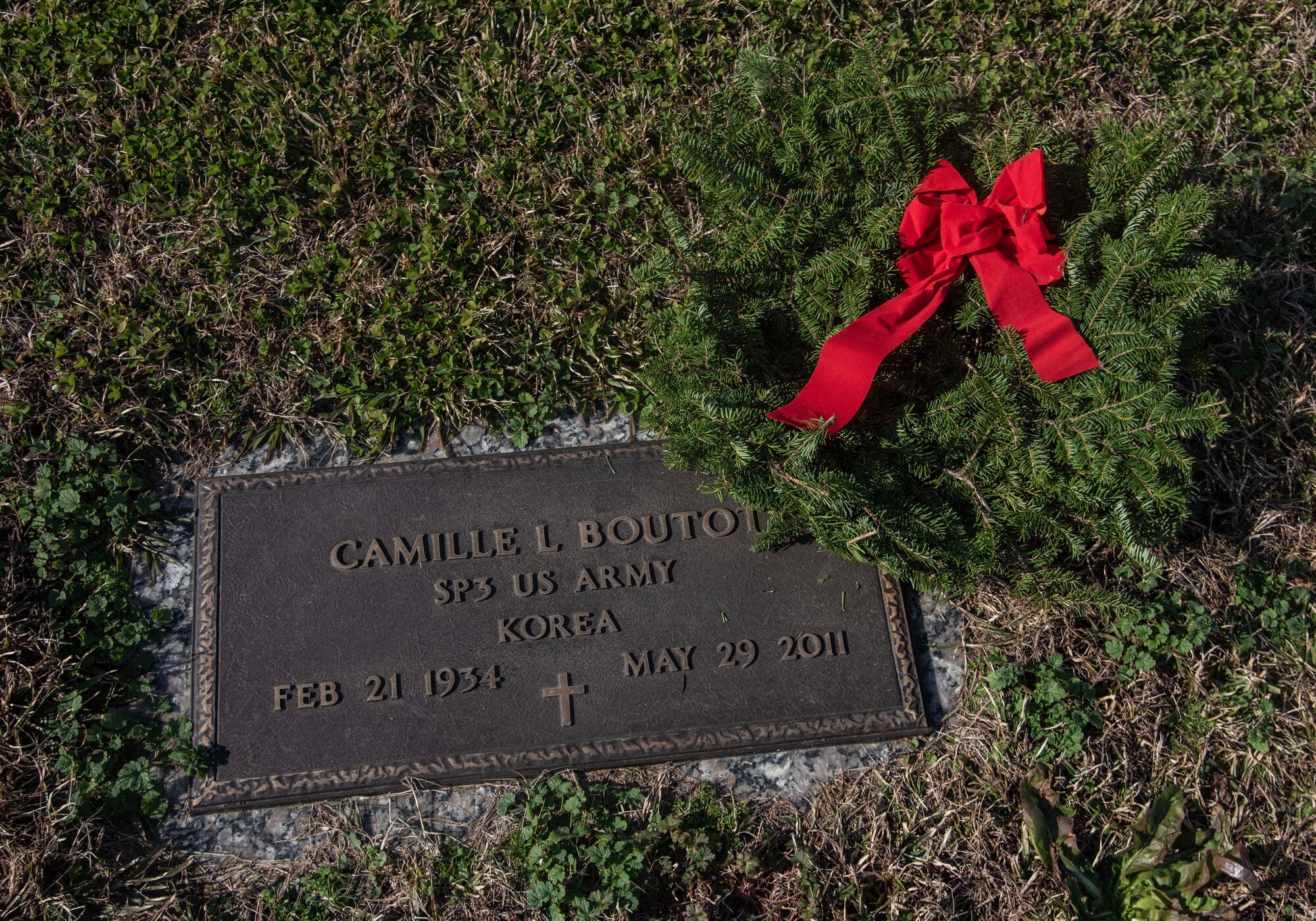 An Airmen places a Christmas wreath on a veteran's grave during the Wreaths Across America event.