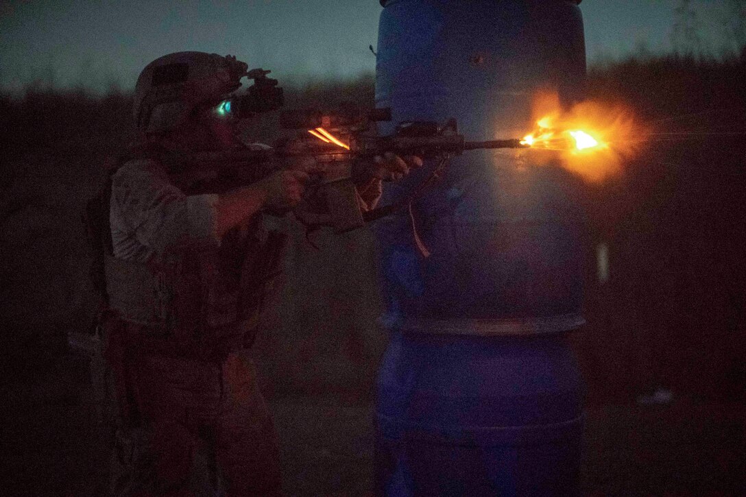 A Marine fires a weapon at night.
