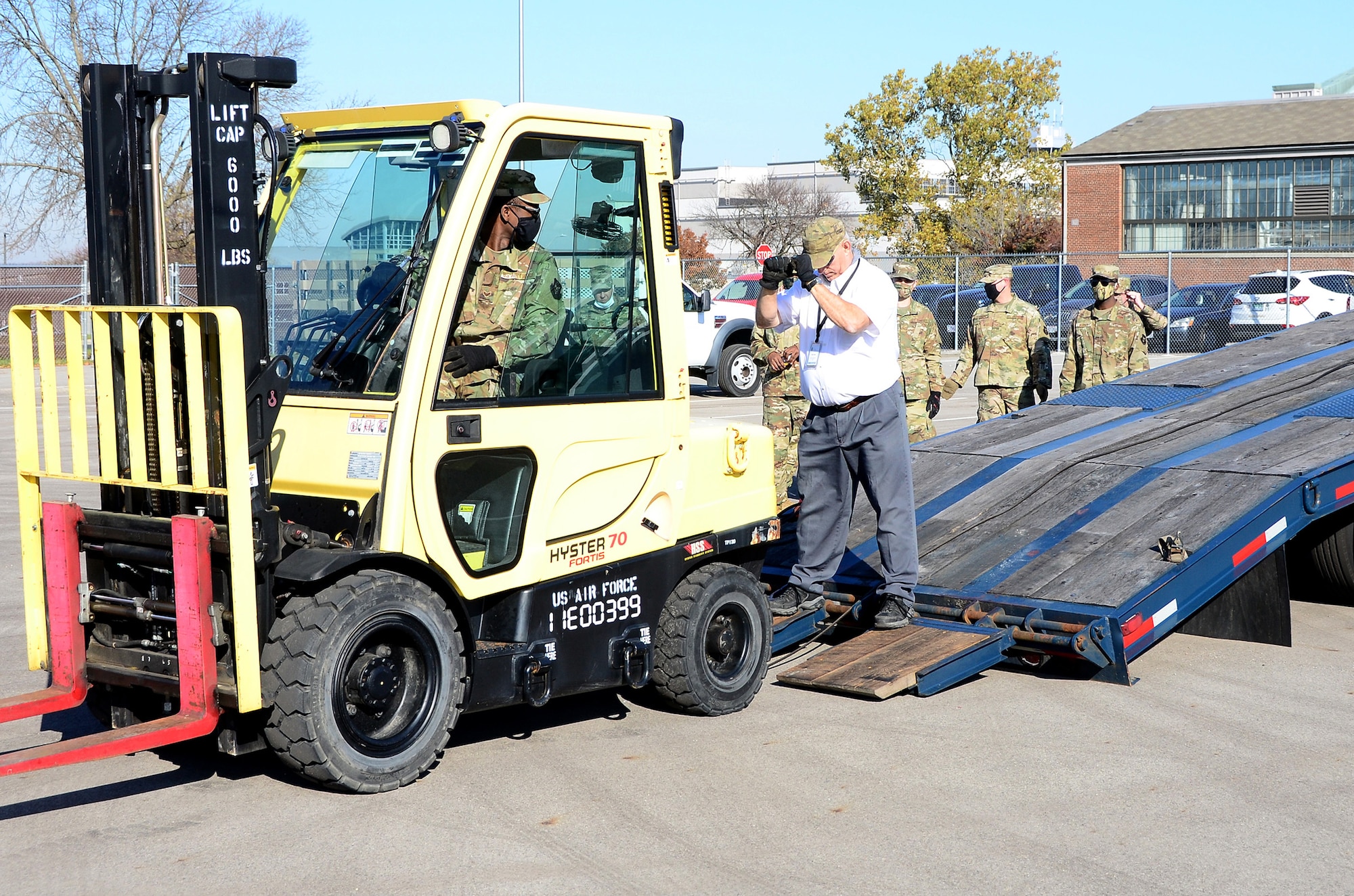 Michael Heaton, an 88th Logistics Readiness Squadron driver, signals Senior Airman Luke Barnes, 445th Logistics Readiness Squadron ground transportation operator, to stop as he guides him up the tilt bed trailer, Nov. 6, 2020, Wright-Patterson Air Force Base, Ohio. Ensuring the tires of the forklift are lined up with the trailer is paramount to prevent damage while preparing the vehicle for transport as quickly as possible.