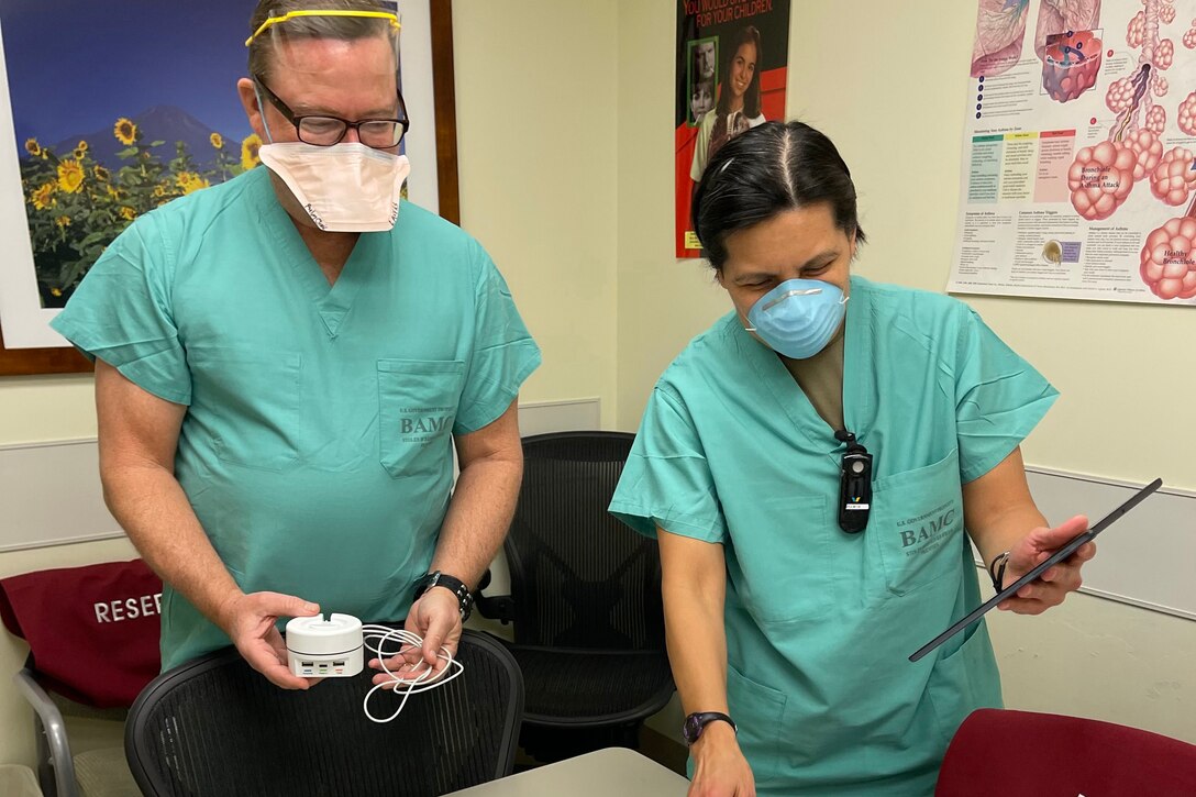 Two health care workers handle equipment.