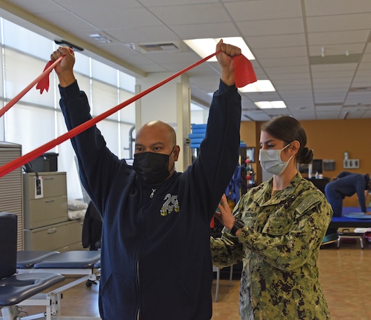 Lt. Erin Kocher assists a Chief Petty Officer with shoulder-strengthening exercises in the Physical Therapy Department of the Adult Medical Care Facility, a branch clinic of Naval Hospital Twentynine Palms.
