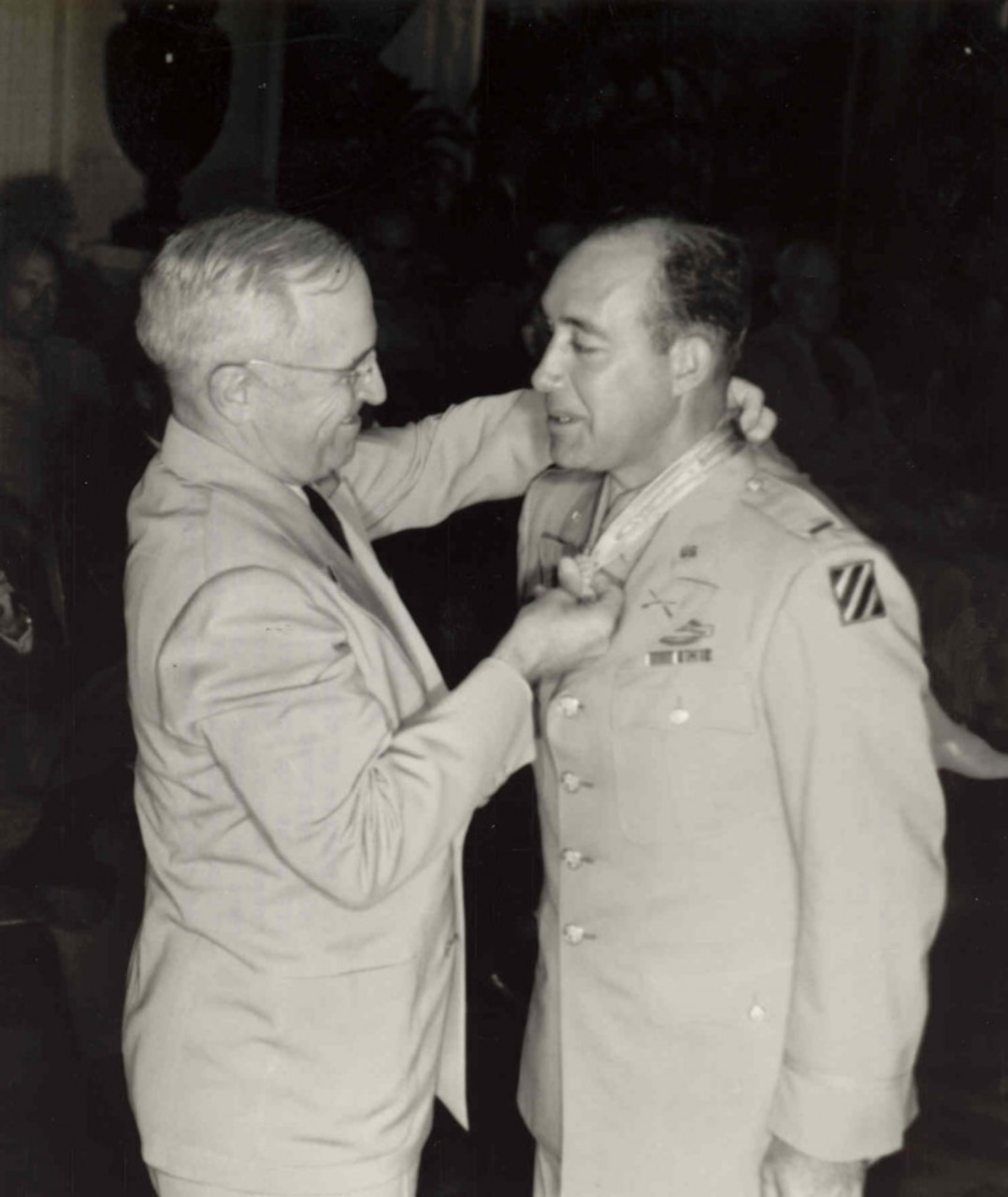 A man puts a medal around another man's neck.