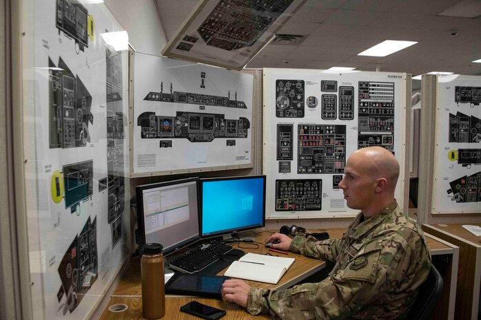 man sits a computer desk