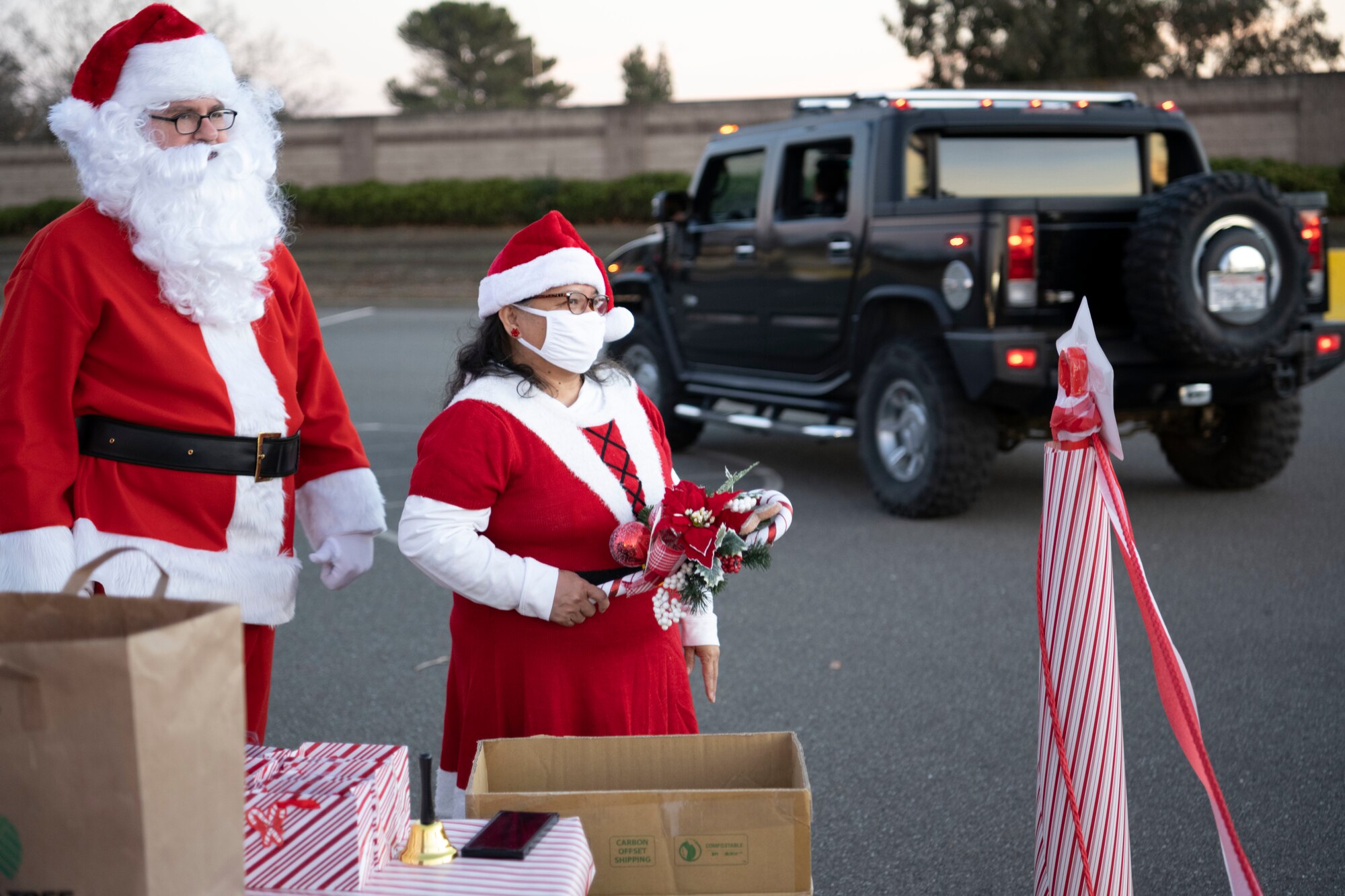 Retired U.S. Air Force Master Sgt. Michael Ward, accounts payable technician at the 60th Aerial Port Squadron, left, and spouse Susan Ward, dietary technician at 60th Medical Group, prepare to hand out gifts Dec. 18 at the Candy Cane Lane drive-thru at Travis Air Force Base, California. During the event, volunteers handed out 260 gift bags to Airmen and their families. (U.S. Air Force photo by Airman 1st Class Alexander Merchak)