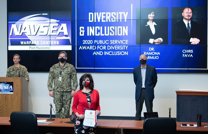 From left on stage: NSWC PHD Executive Officer Lt. Cmdr. Travis Harlow, Commanding Officer Capt. Andrew Hoffman and Technical Director Paul Mann (far right on stage) present at the All Hands live the Diversity and Inclusion 2020 Public Service Award to Ramona Armijo (center front) and Chris Fava (virtually) Wednesday, Dec. 9.