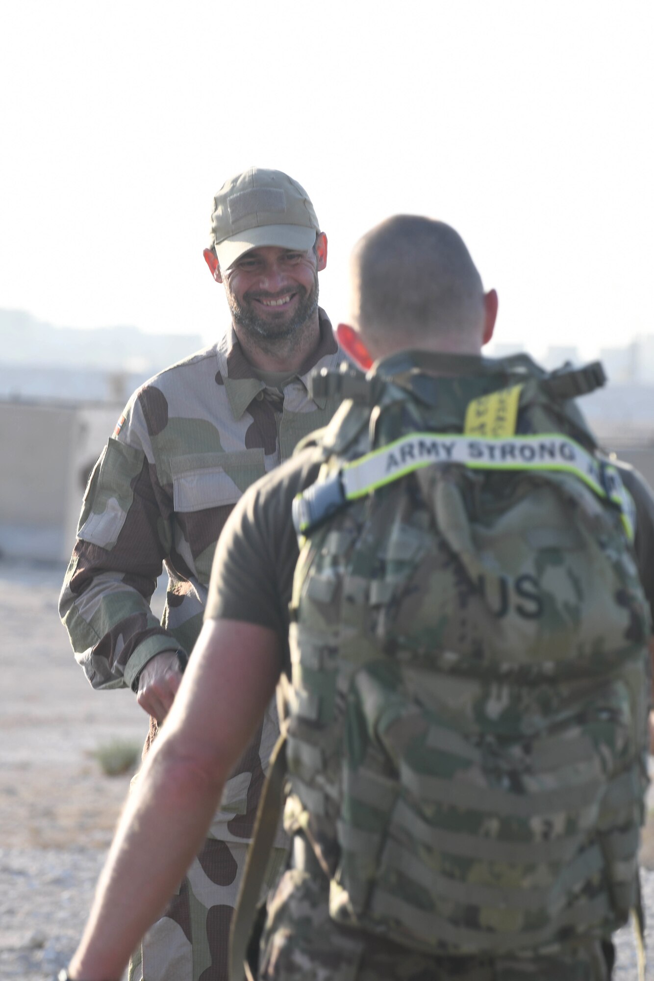Norwegian armed forces Capt. Magne Rambo, deployed to Al Udeid Air Base, Qatar, as part of the U.S. Central Command Partner Integration Enterprise, greets U.S. Army Chief Warrant Officer Thomas Iverson at the Norwegian foot march progress checkpoint Dec. 5, 2020. Rambo supervised the event, a Norwegian military tradition dating back to 1915, 10 years after Norway gained its independence from Sweden, which brought together nearly 120 other coalition members, including Americans, Australians, British and Canadians, and New Zealanders for a 30-kilometer (18.6-mile) challenge. (U.S. Air Force photo by Staff Sgt. Kayla White)