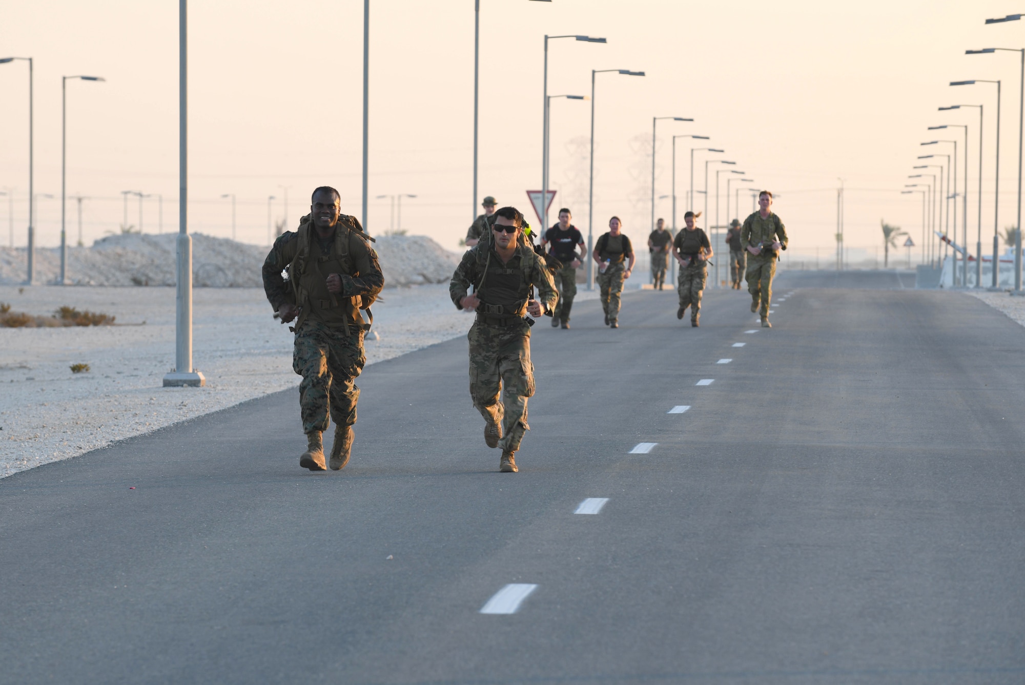 U.S. Marine Corps Chief Warrant Officer Gethro Metellus and U.S. Army 1st Lt. Keven Cordero, deployed to Al Udeid Air Base, Qatar, as part of U.S. Forces Afghanistan, run together while participating in the traditional 30-kilometer (18.6-mile) Norwegian foot march event. The tradition began in 1915, 10 years after Norway gained its independence from Sweden and has become a rite of passage for all Norwegian military members. They joined nearly 120 other coalition members, including Americans, Australians, New Zealanders, British and Canadians who participated in the march under the supervision of Norwegian armed forces Capt. Magne Rambo, deployed to Al Udeid AB as part of the U.S. Central Command Partner Integration Enterprise. (U.S. Air Force photo by Staff Sgt. Kayla White)