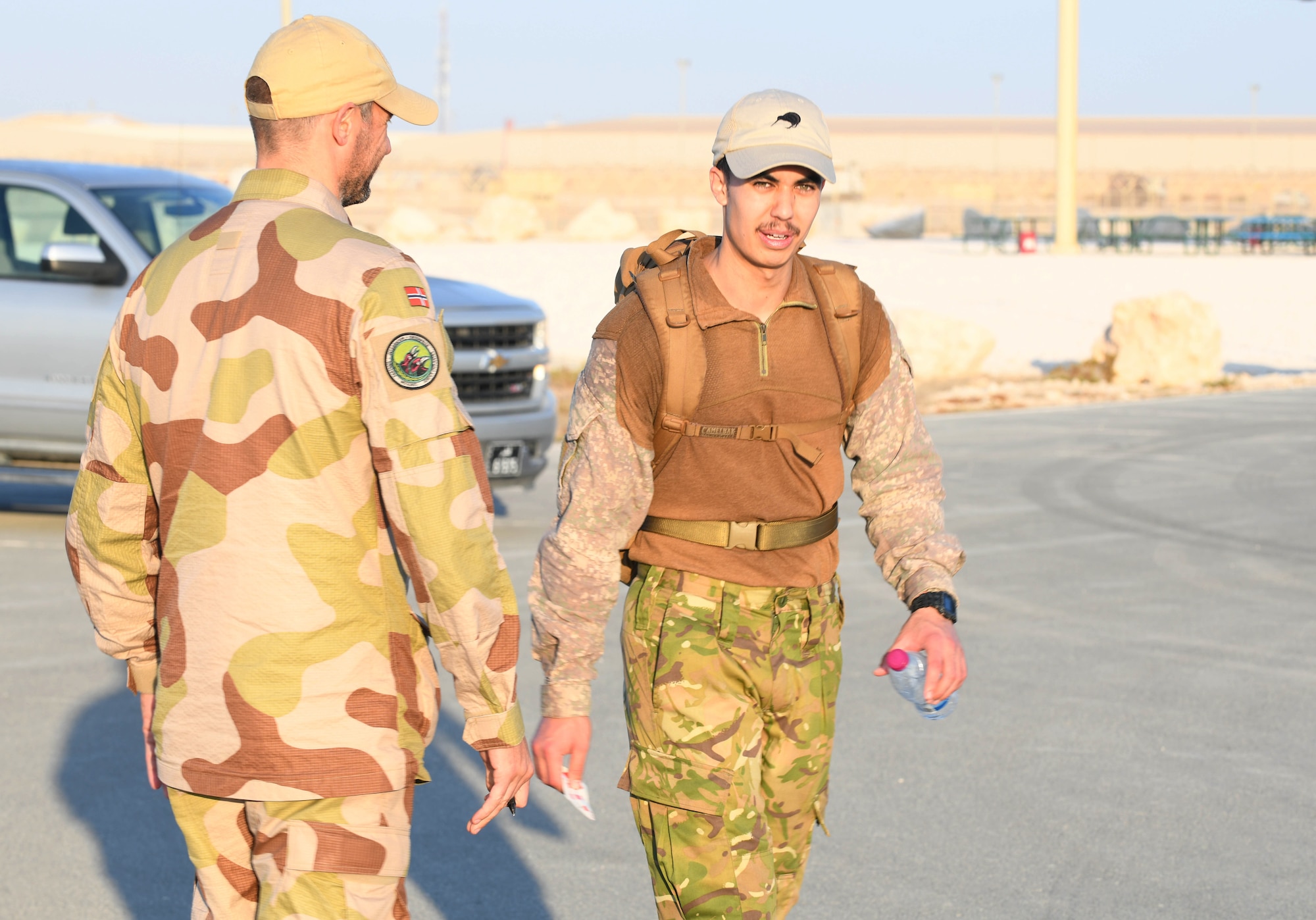 New Zealand army Lance Cpl. Micah Sears walks past Norwegian armed forces Capt. Magne Rambo at the progress checkpoint during the traditional 30-kilometer (18.6-mile) Norwegian foot march event held at Al Udeid Air Base, Qatar, Dec. 5, 2020. The tradition began in 1915, 10 years after Norway gained its independence from Sweden and has become a rite of passage for all Norwegian military members. Sears joined nearly 120 other coalition members, including Americans, Australians, British and Canadians who participated in the march under the supervision of Rambo, deployed to Al Udeid AB as part of the U.S. Central Command Partner Integration Enterprise. (U.S. Air Force photo by Staff Sgt. Kayla White)