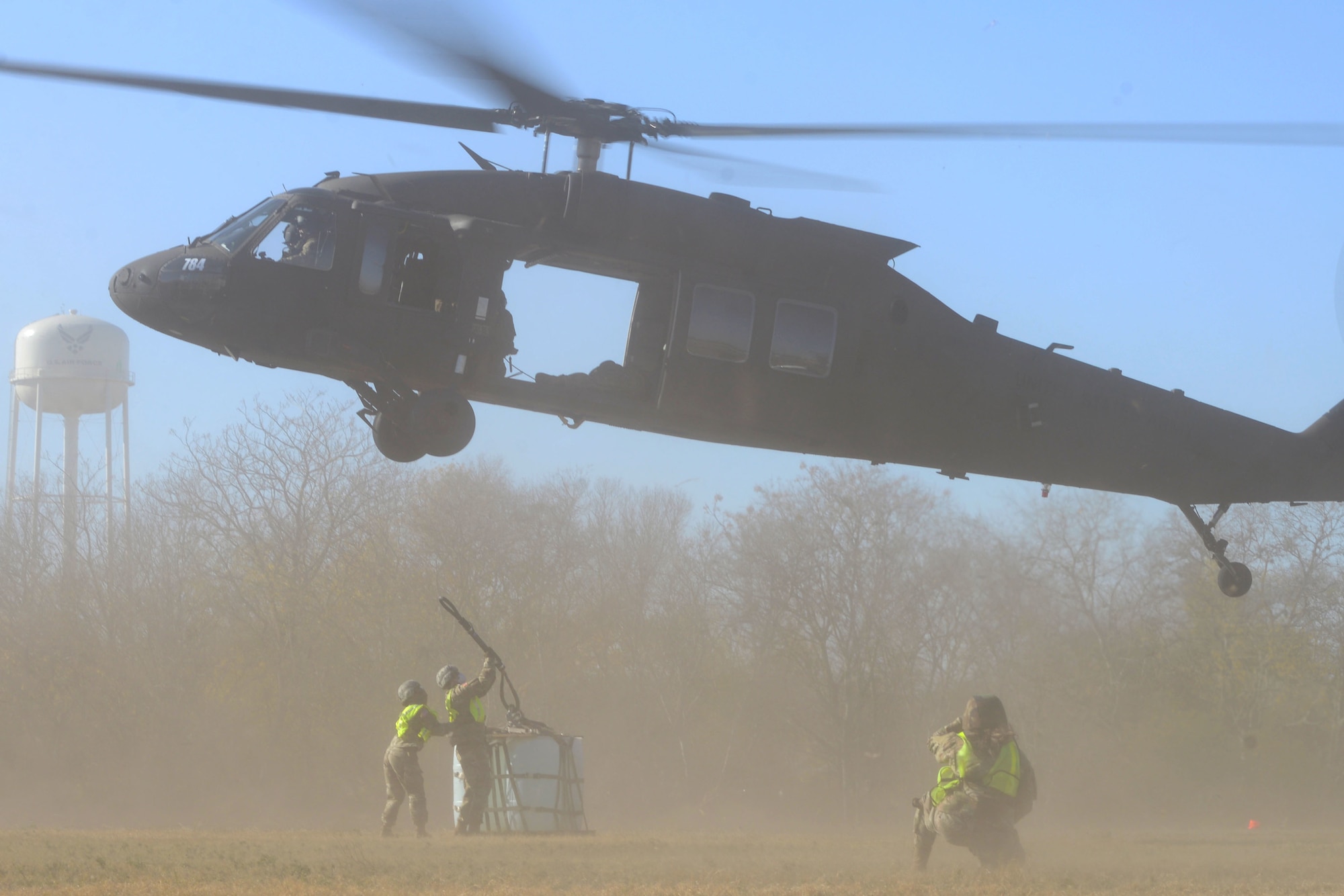 Operation Nightstorm team members work together to attach a sling load to a UH-60 Black Hawk helicopter Dec. 15, 2020, at Joint Base San Antonio-Chapman Training Annex, Texas. (U.S. Air Force photo by Tech. Sgt. Samantha Mathison)