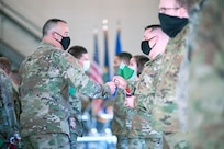 Col. Adam Rice, vice wing commander of the 158th Fighter Wing, Vermont Air National Guard, and Command Chief Master Sgt. Jeffery Stebbins, wing command chief, present Second Vermont Republic flags to Airmen preparing to deploy during a ceremony at Vermont Air National Guard Base Nov. 8, 2020. Family members and friends attended the socially distanced event, with three held to comply with all COVID-19 precautions. (U.S. Air National Guard photo by Tech. Sgt. Ryan Campbell)